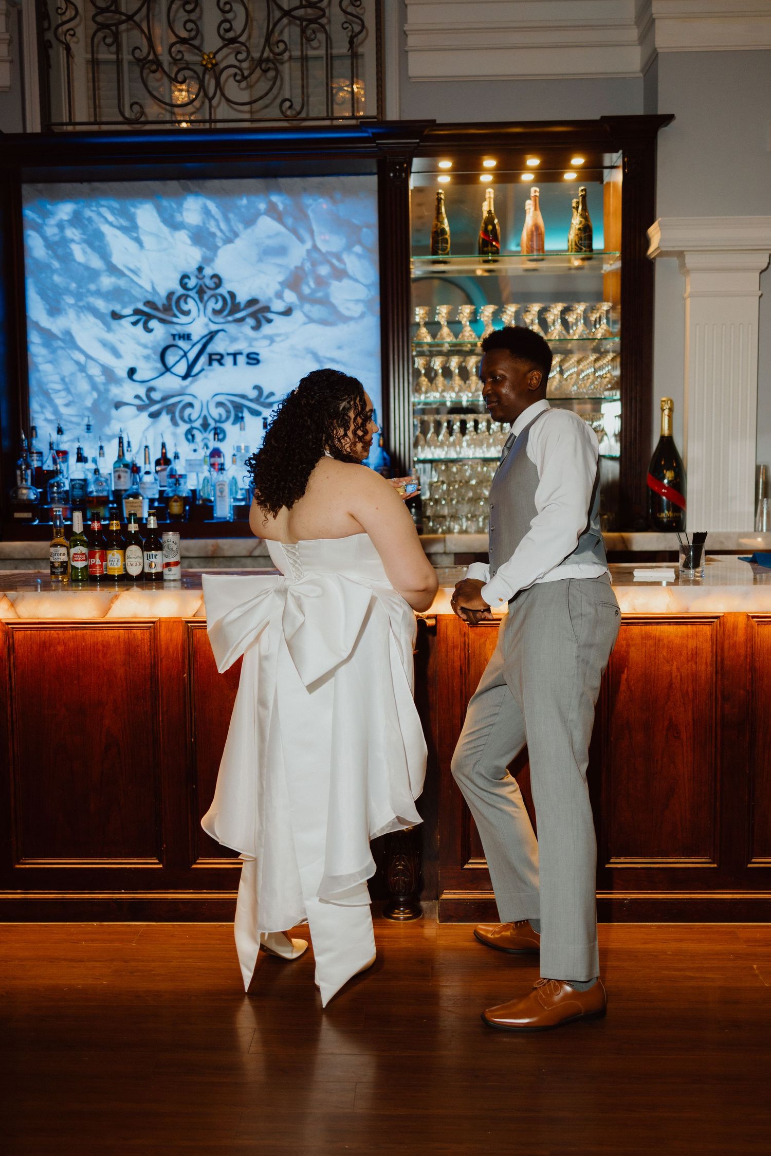 Bride and groom walking together into a warmly lit reception lounge.