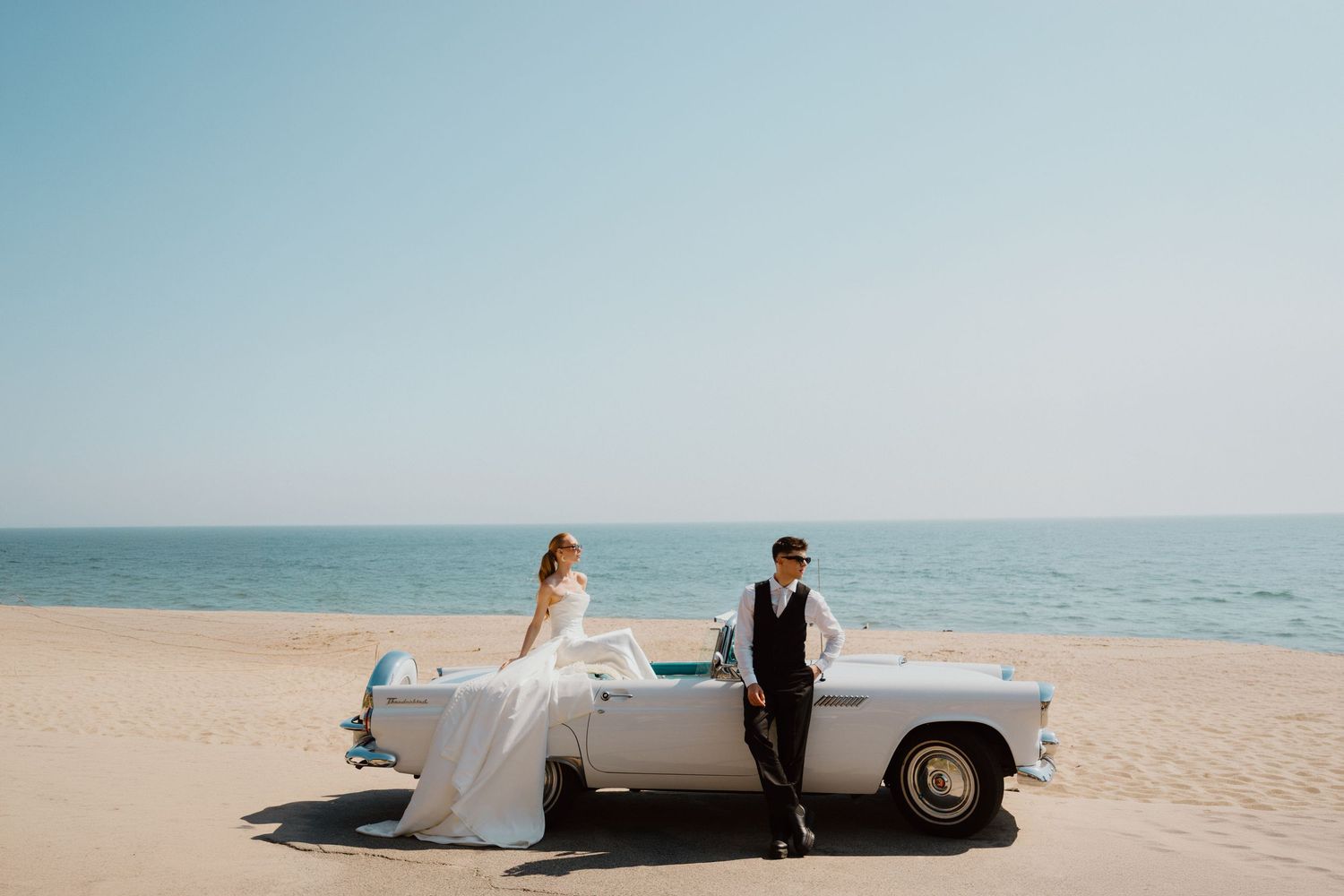 Bride and groom beside a vintage car on the beach during an oceanfront elopement.