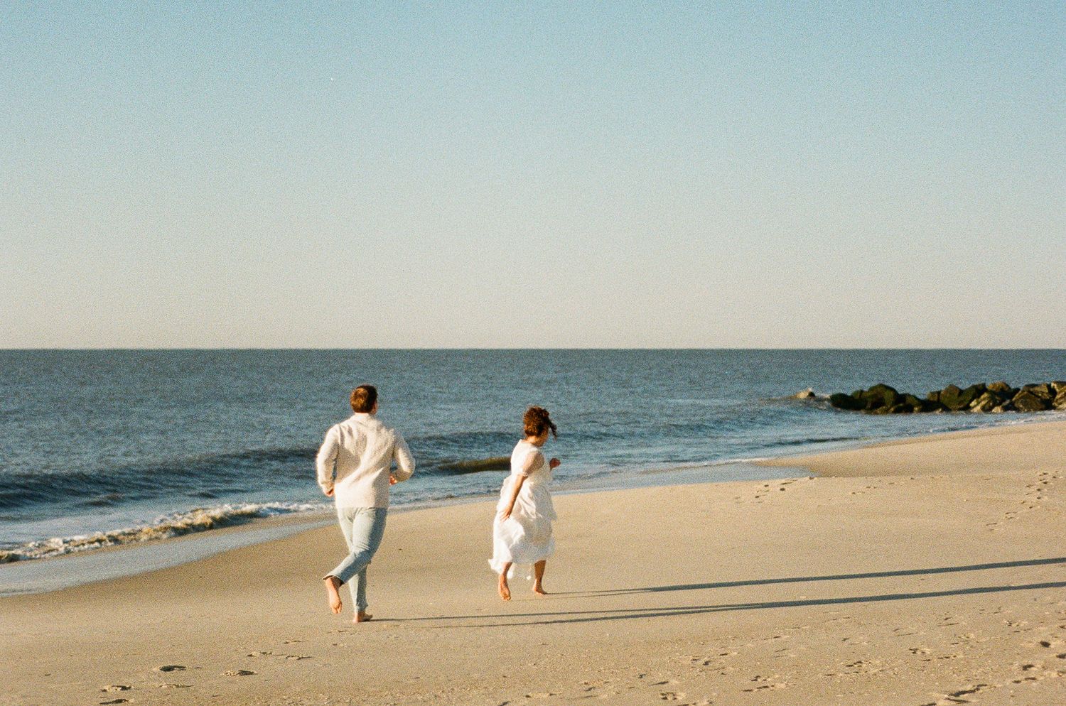 Couple walking together along the shoreline during a beach elopement.