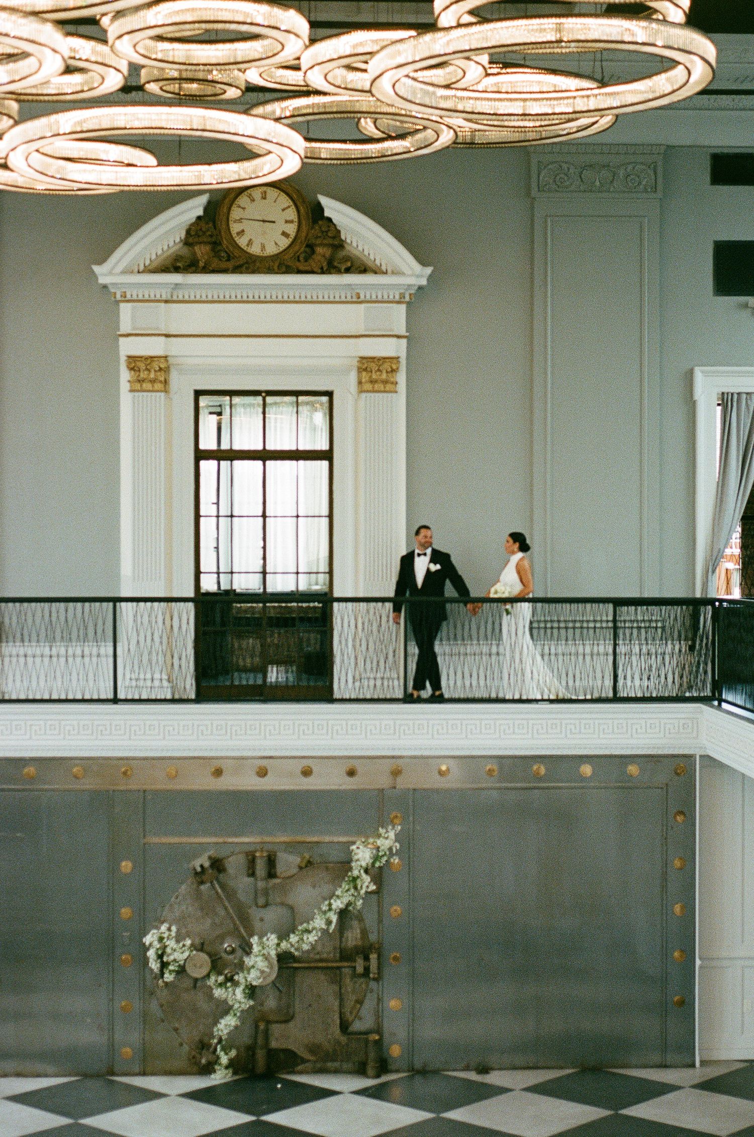 Wedding venue interior with hanging chandeliers and a small figure standing in the grand doorway.