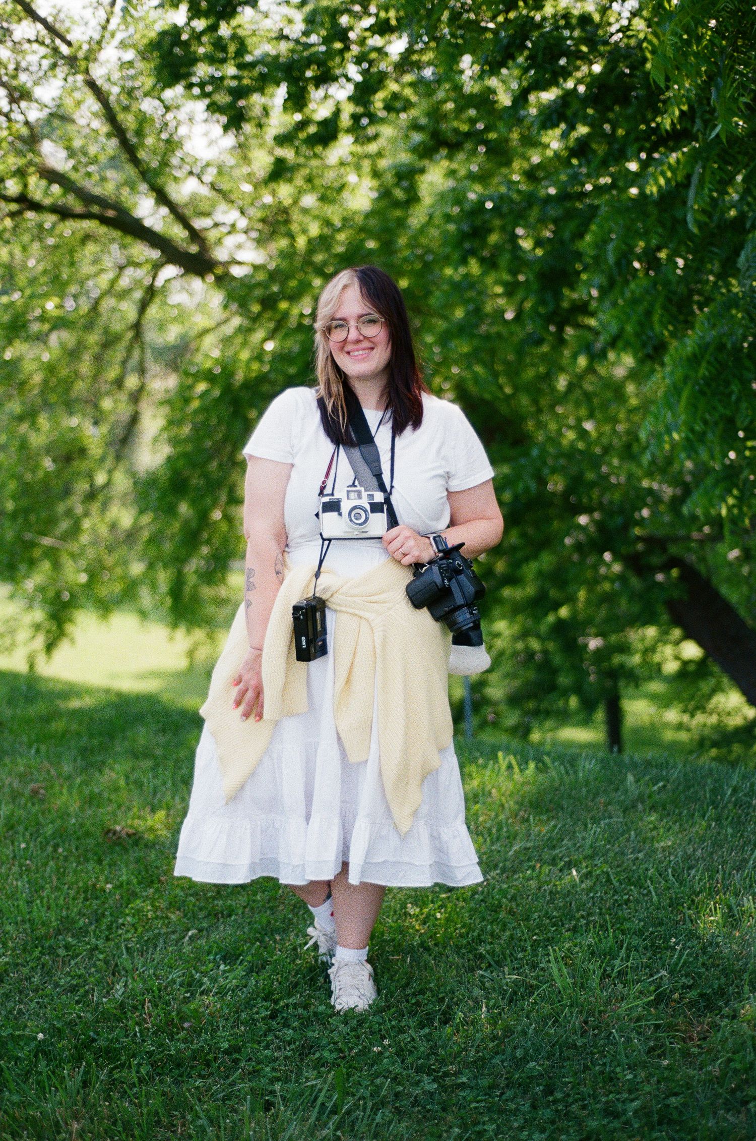 Woman in a white dress standing on a green lawn.