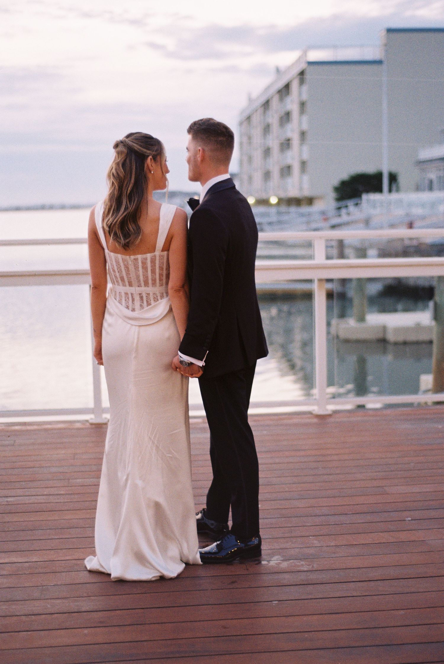 Couple holding hands on a rooftop terrace at dusk.