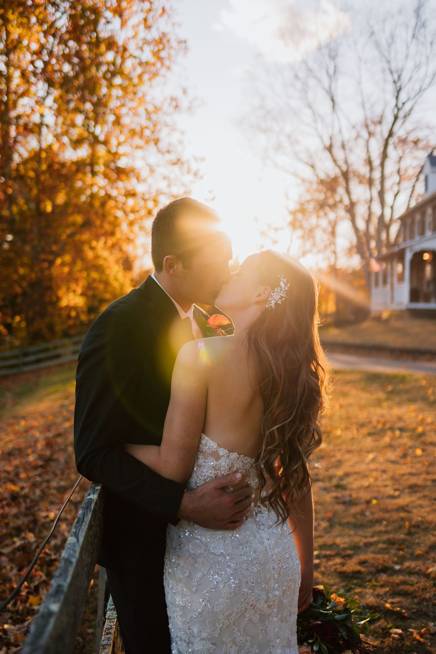 Couple kissing in a glowing autumn park at golden hour.