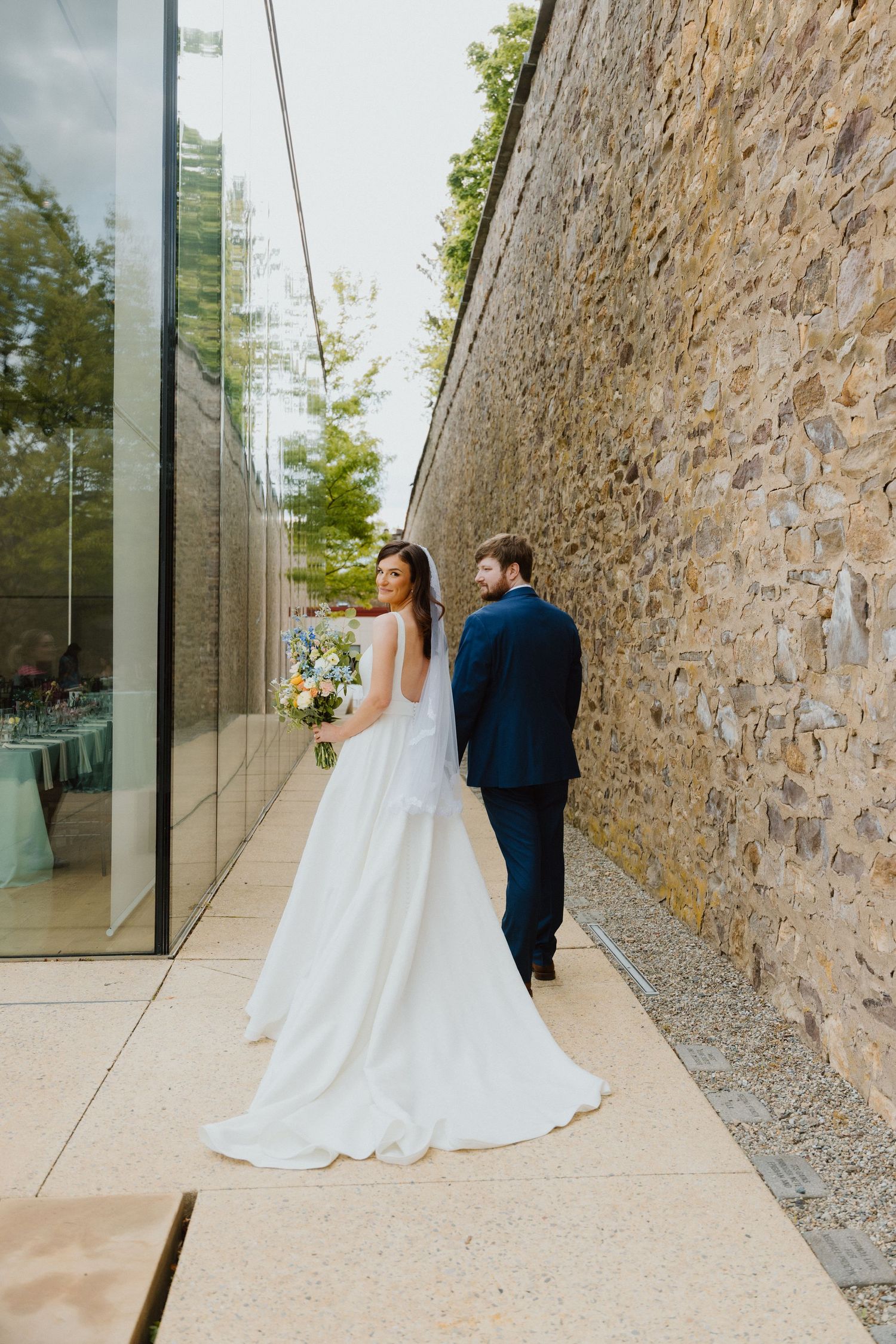 Bride and groom walking hand in hand down a narrow stone alleyway.