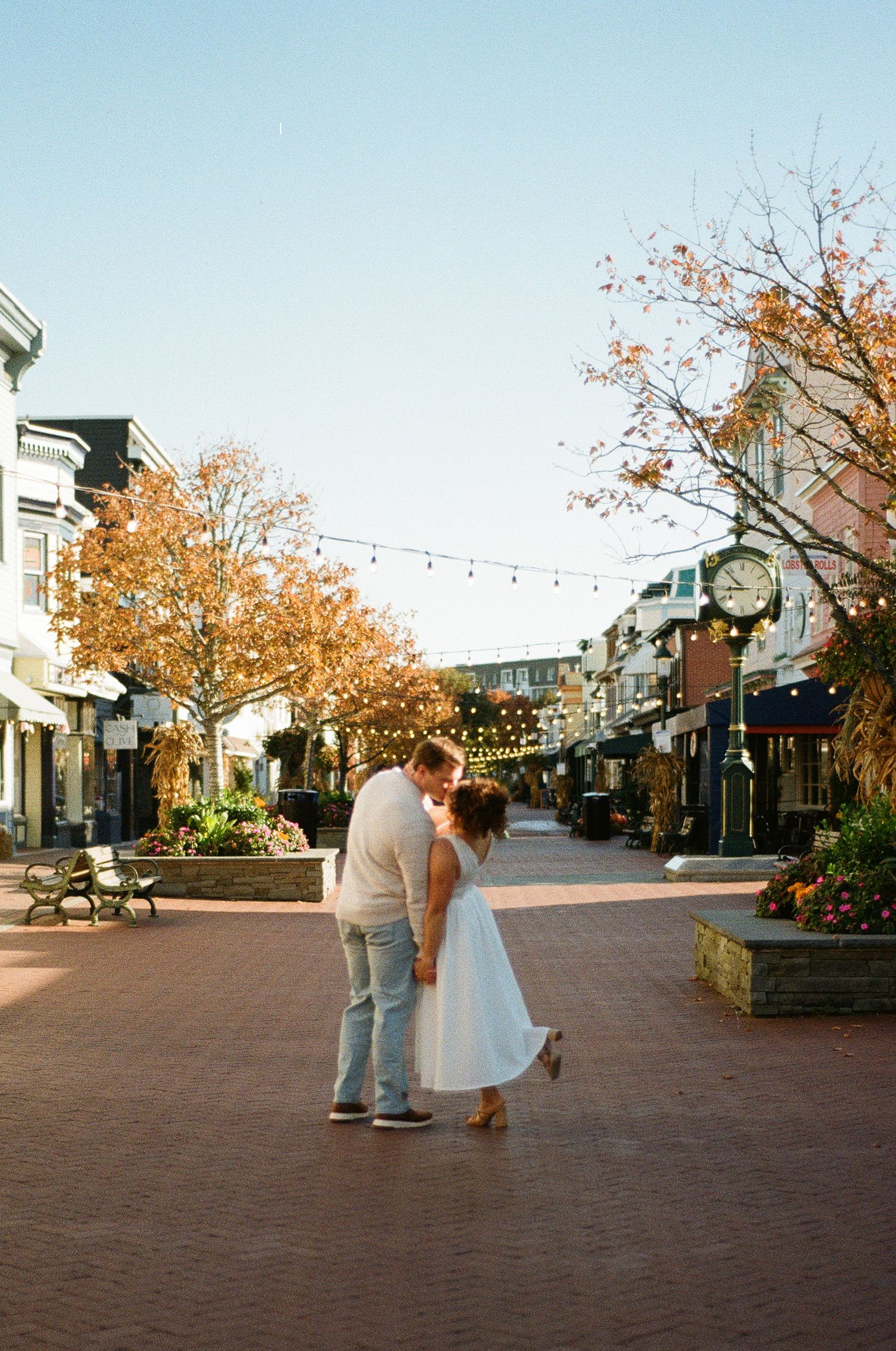 Bride and groom walking hand in hand down a tree-lined street.