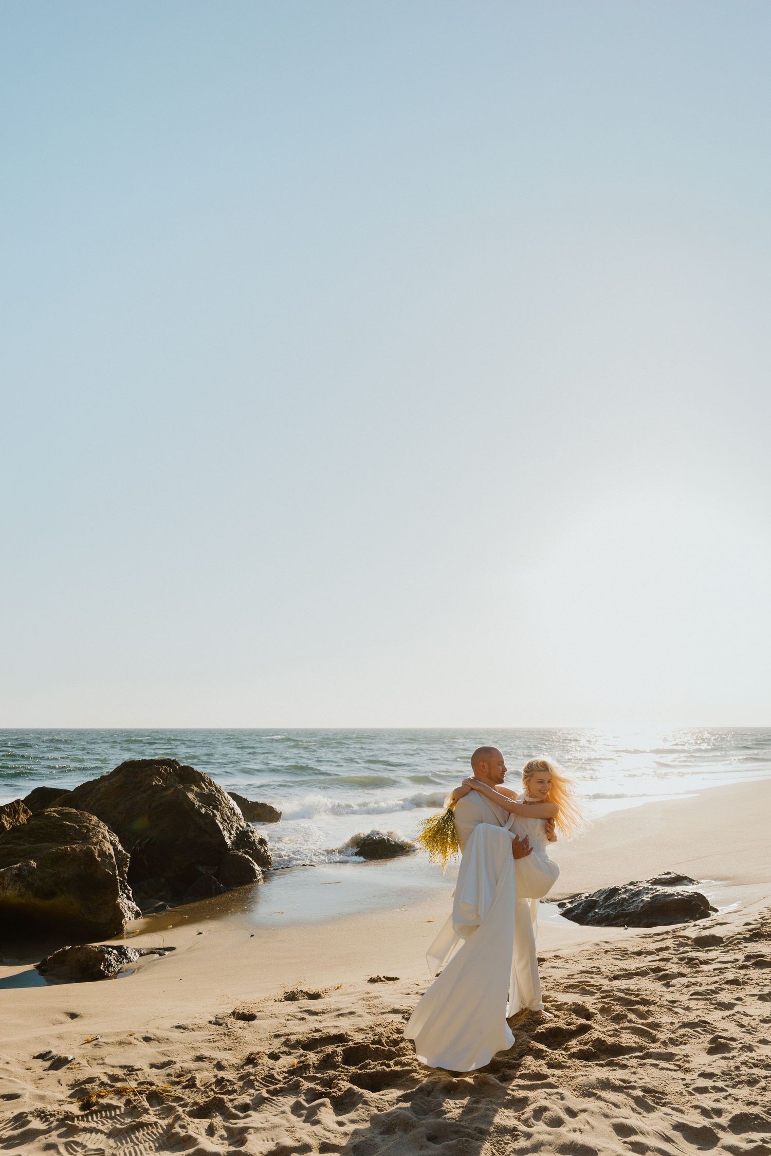 Bride and groom on a rocky beach overlooking the ocean during a seaside elopement.