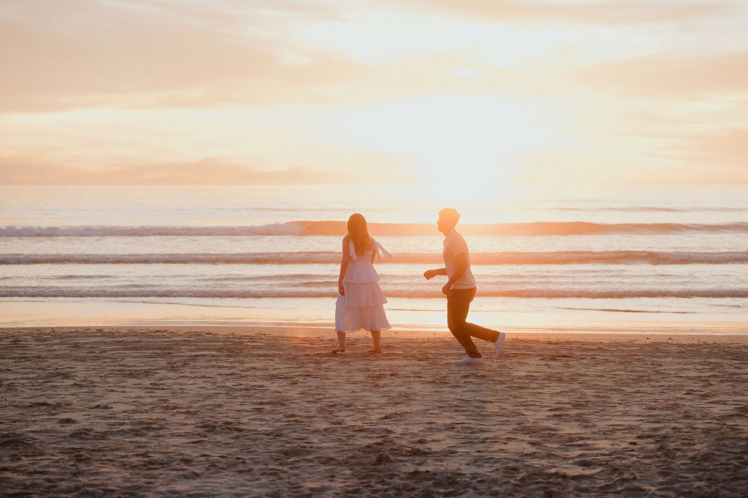 Couple holding hands on the beach at sunset during a coastal elopement.