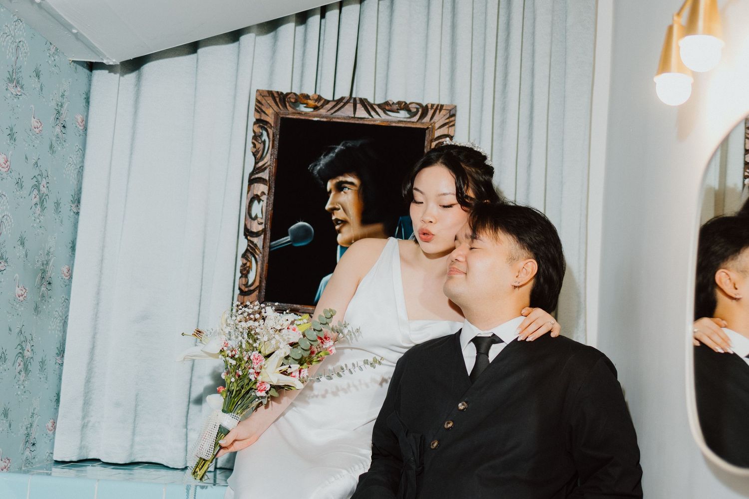 Editorial bride and groom portrait beside an ornate gilded mirror, with soft draped curtains.