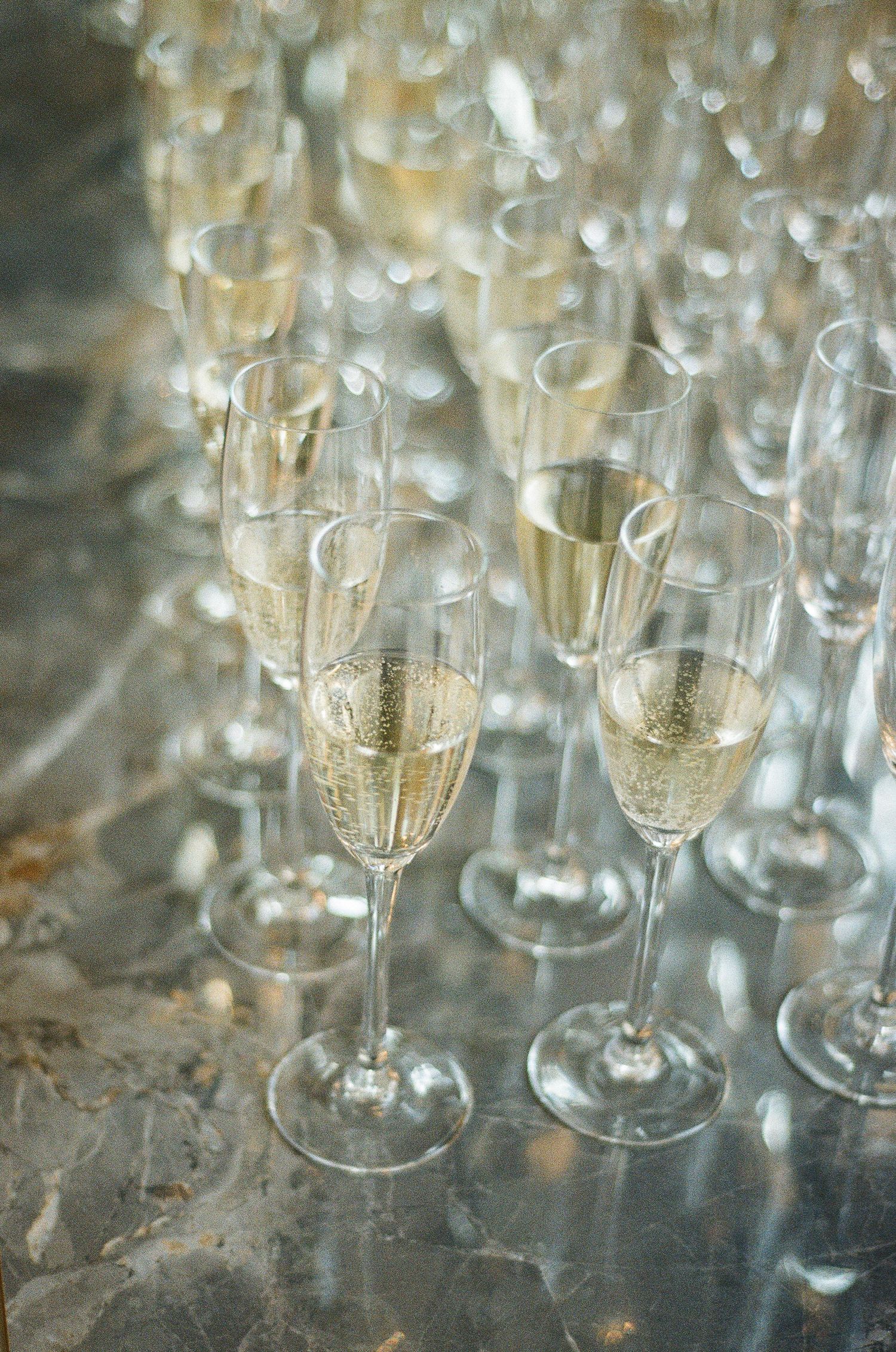 Close-up of a glowing crystal chandelier suspended from a wedding venue ceiling.