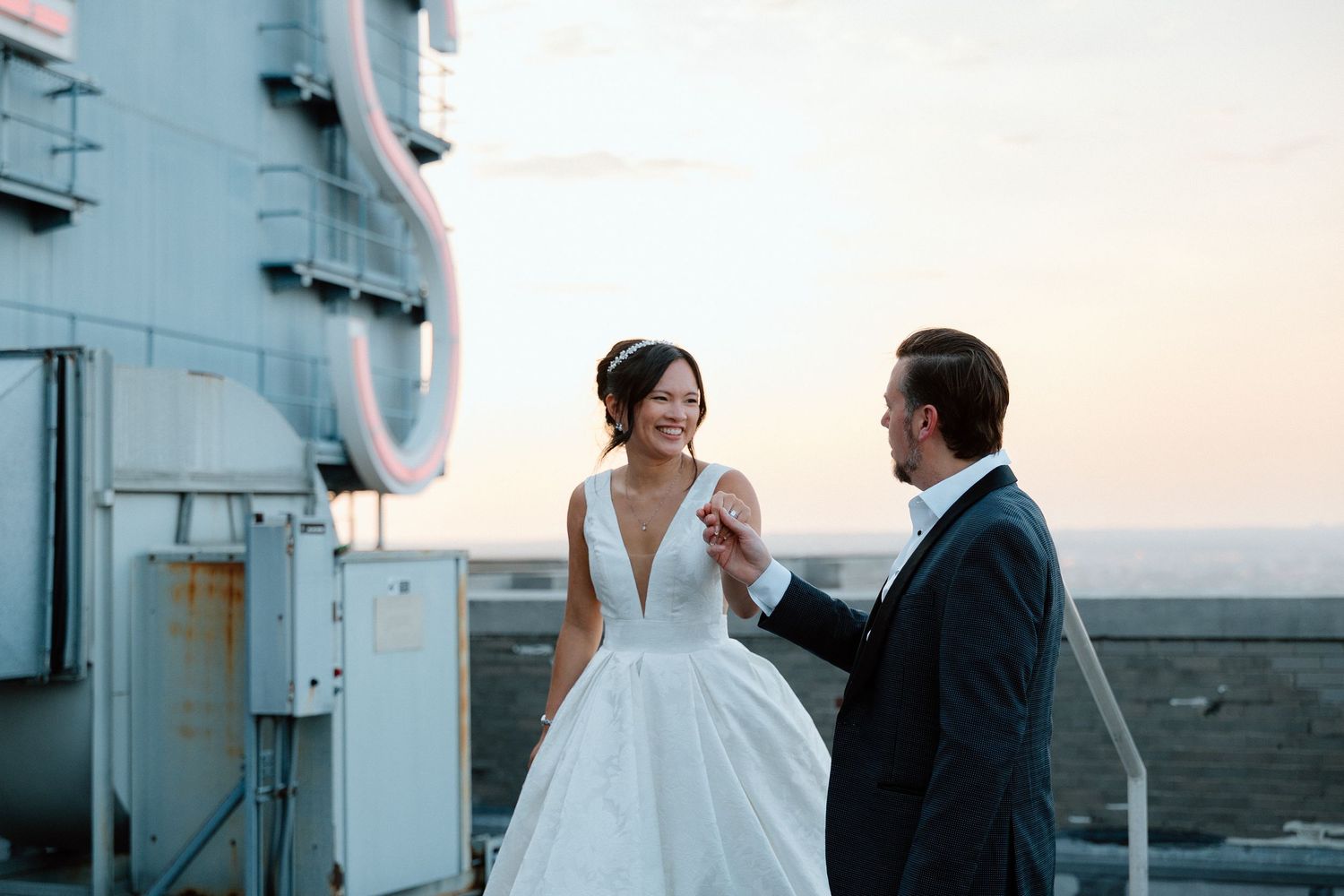 Bride and groom standing close together on a ship's deck against a soft sunset sky, a romantic waterfront wedding portrait.