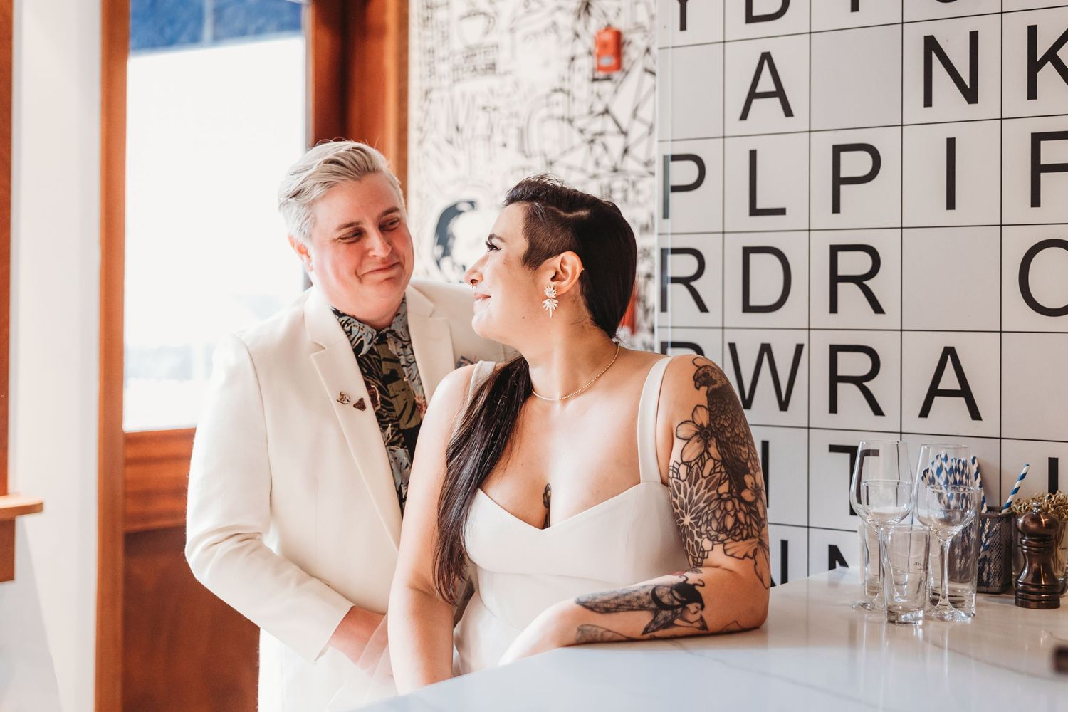 Couple embracing at an indoor wedding reception with a decorative backdrop.