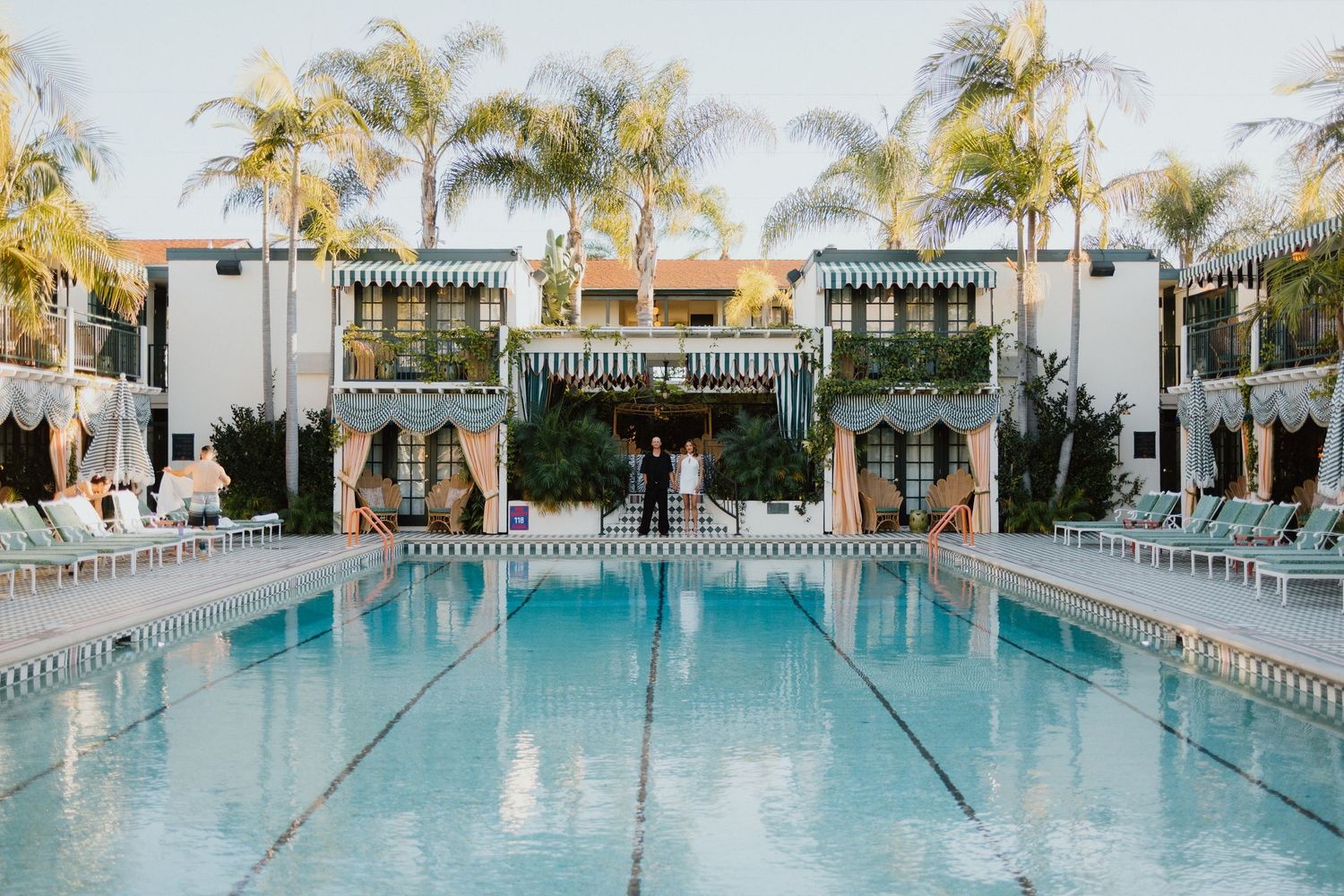 Bride and groom beside a palm-lined resort pool, captured during an editorial destination wedding portrait session.