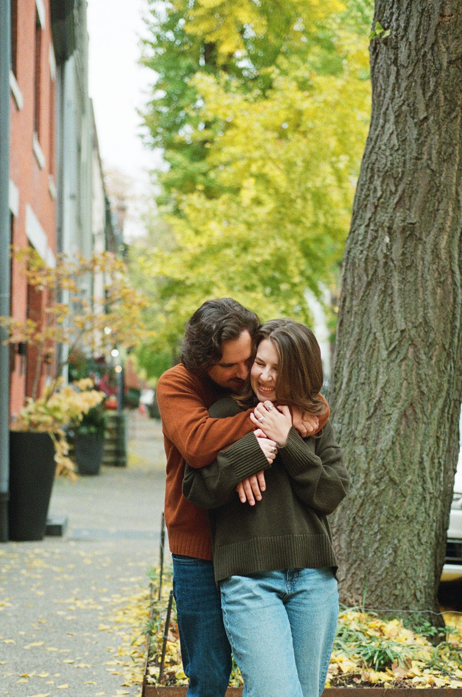 Couple sharing a playful embrace on a city street during an urban engagement session.