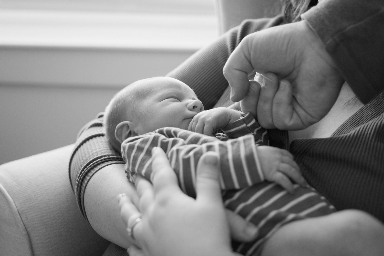 Black and white photo of a newborn cradled in a parent's arms.