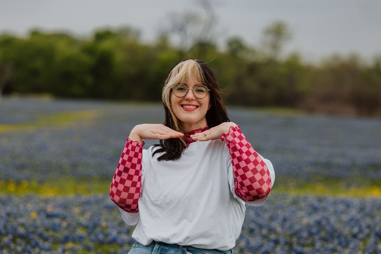 Woman in plaid sitting in a field of bluebonnets.
