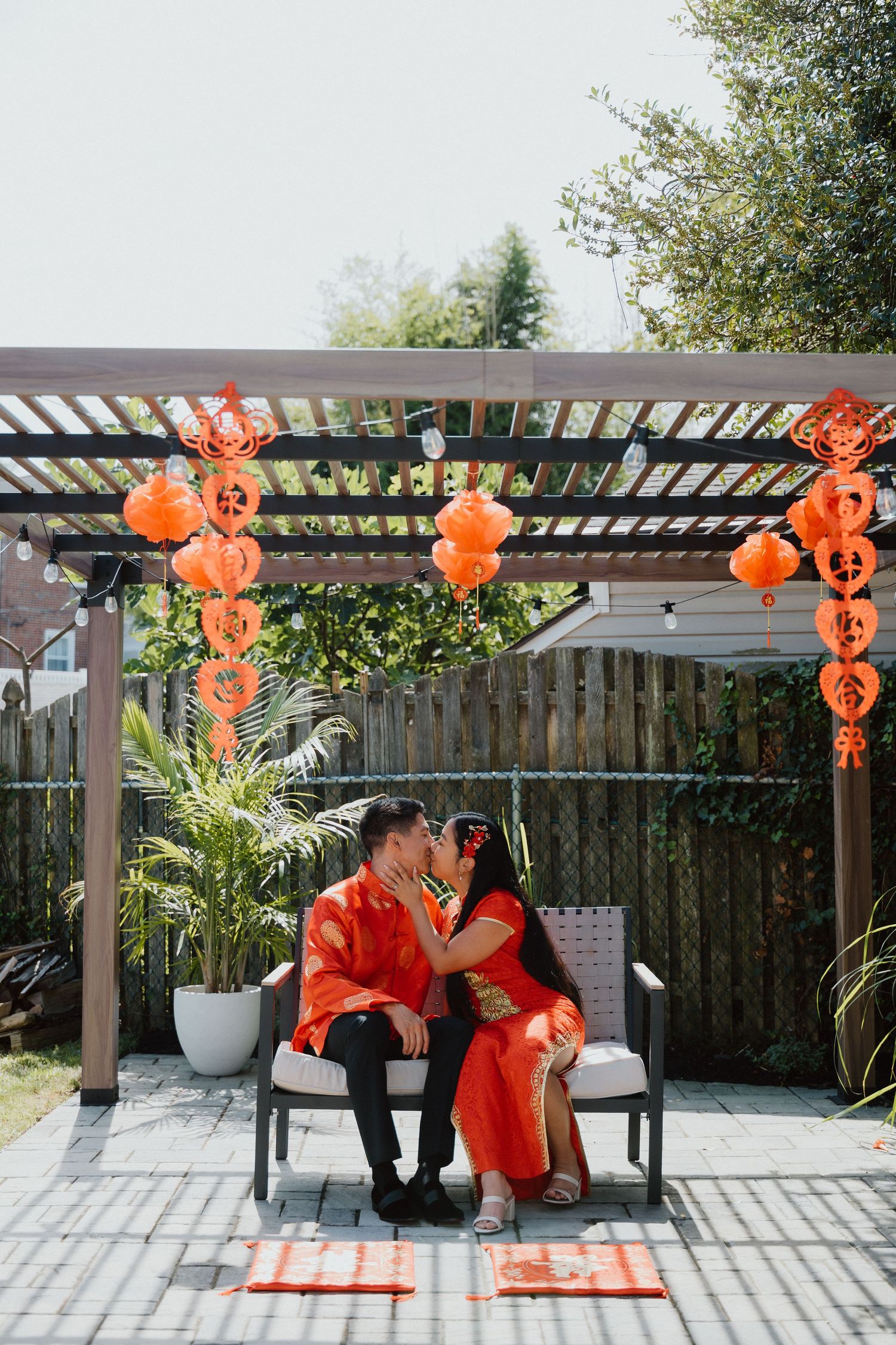 Couple seated at a small table beneath string lights and hanging paper lanterns in a cozy outdoor venue.