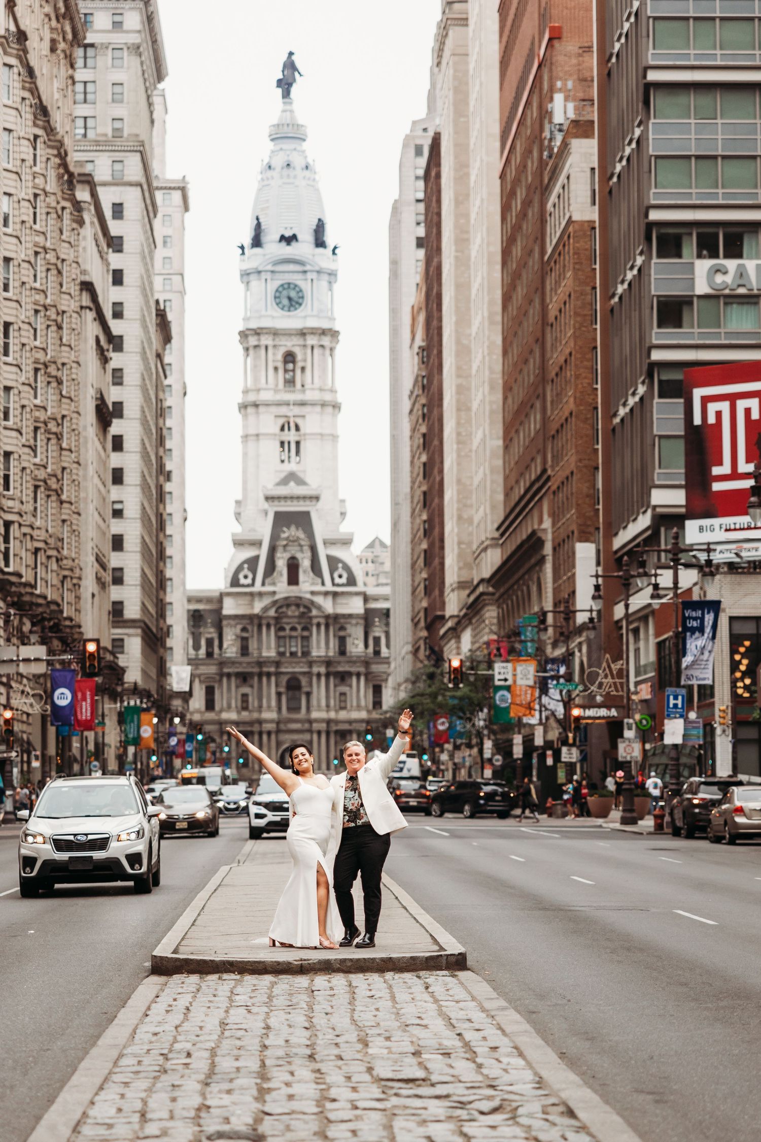 Couple walking down a city street with historic architecture during an urban wedding.