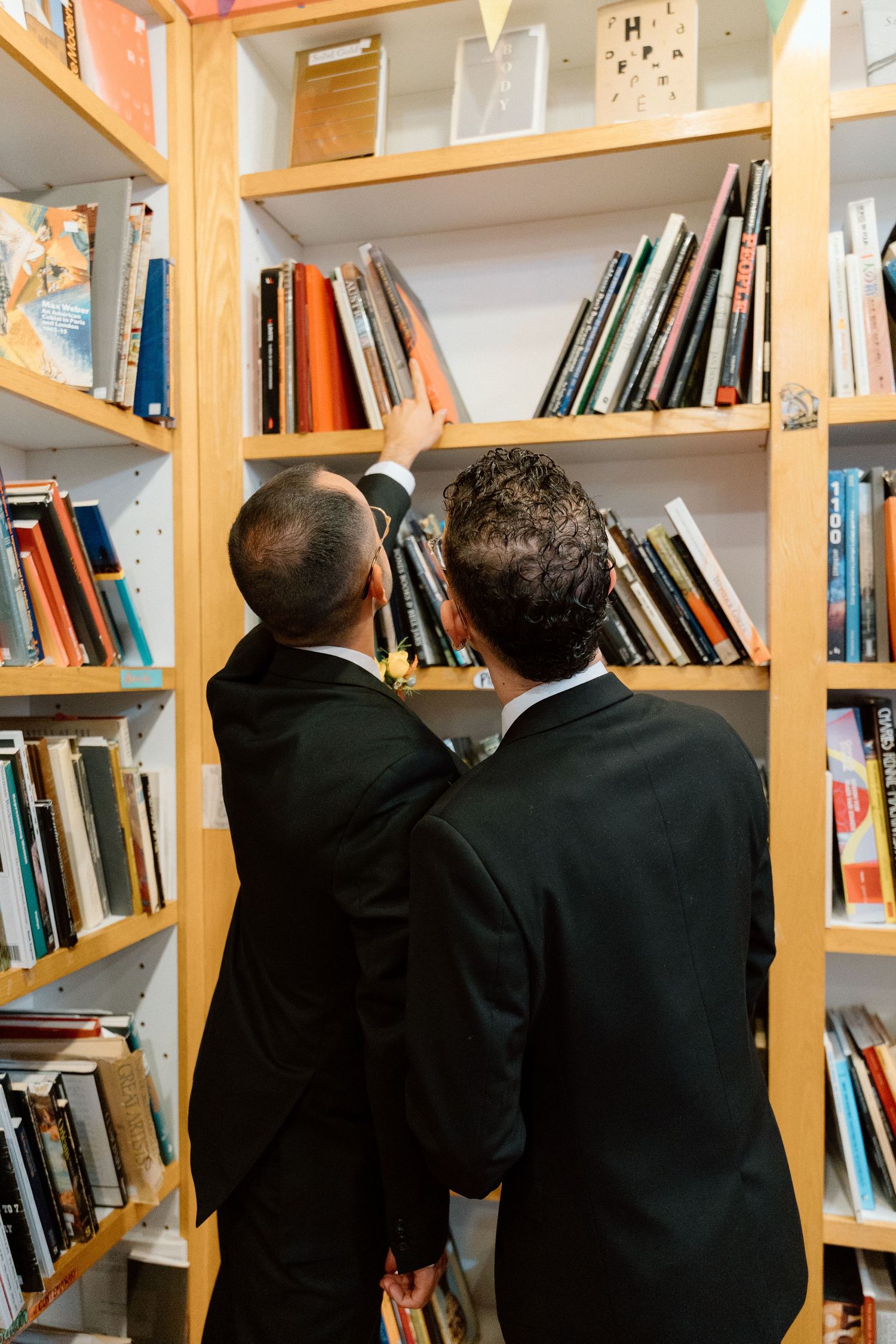 Couple in formal attire standing together in a library during a wedding.