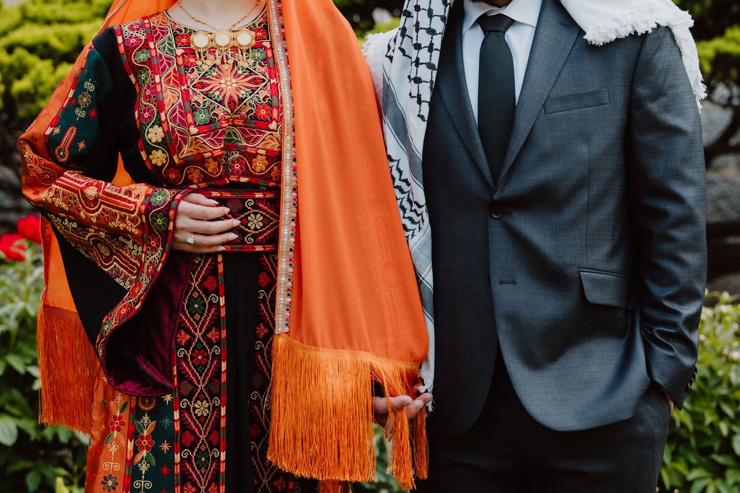 Wedding couple in embroidered orange dupatta and navy suit at outdoor fusion ceremony.