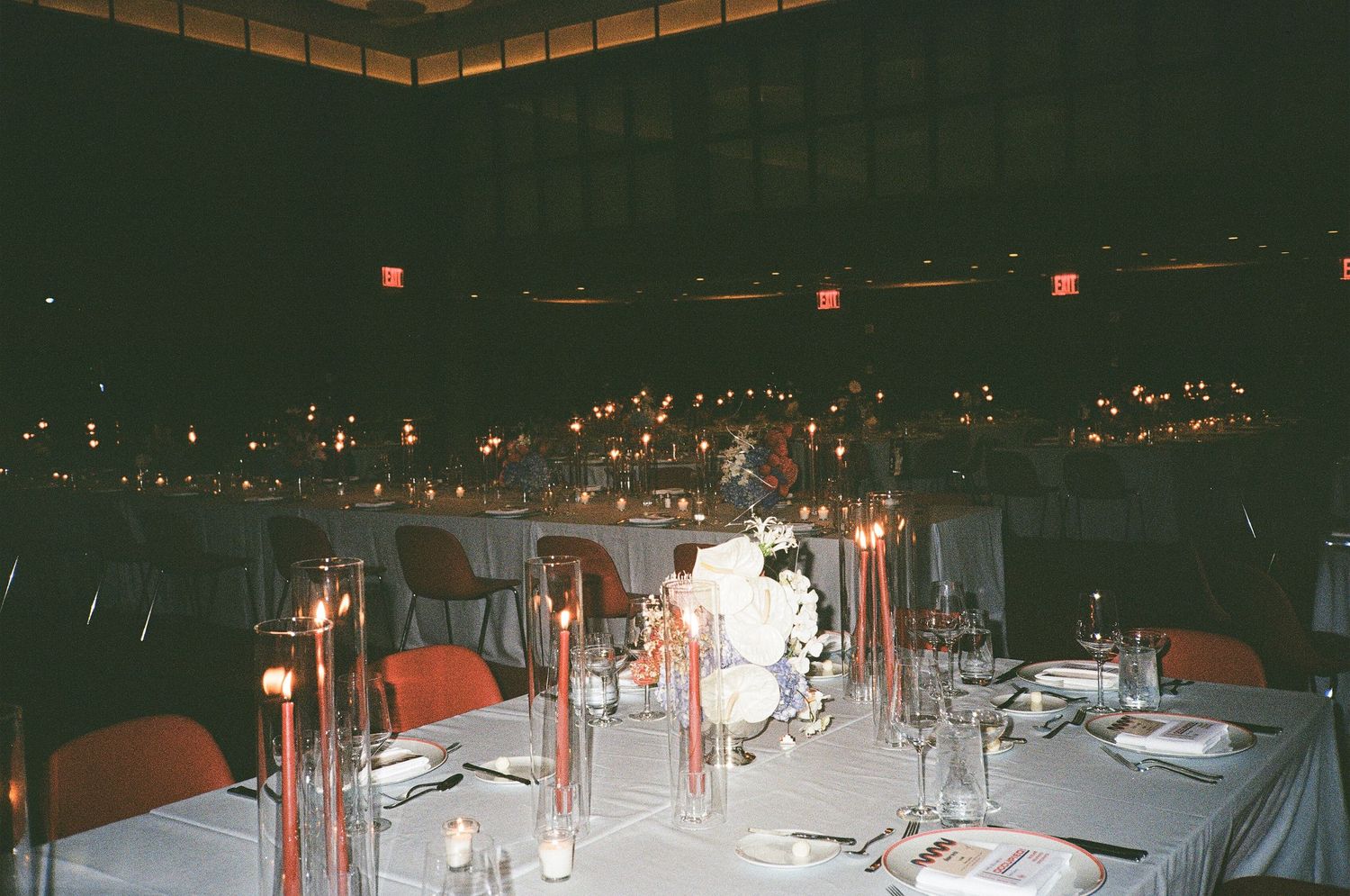Candlelit wedding reception tablescape with taper candles and floral centerpiece at dusk.
