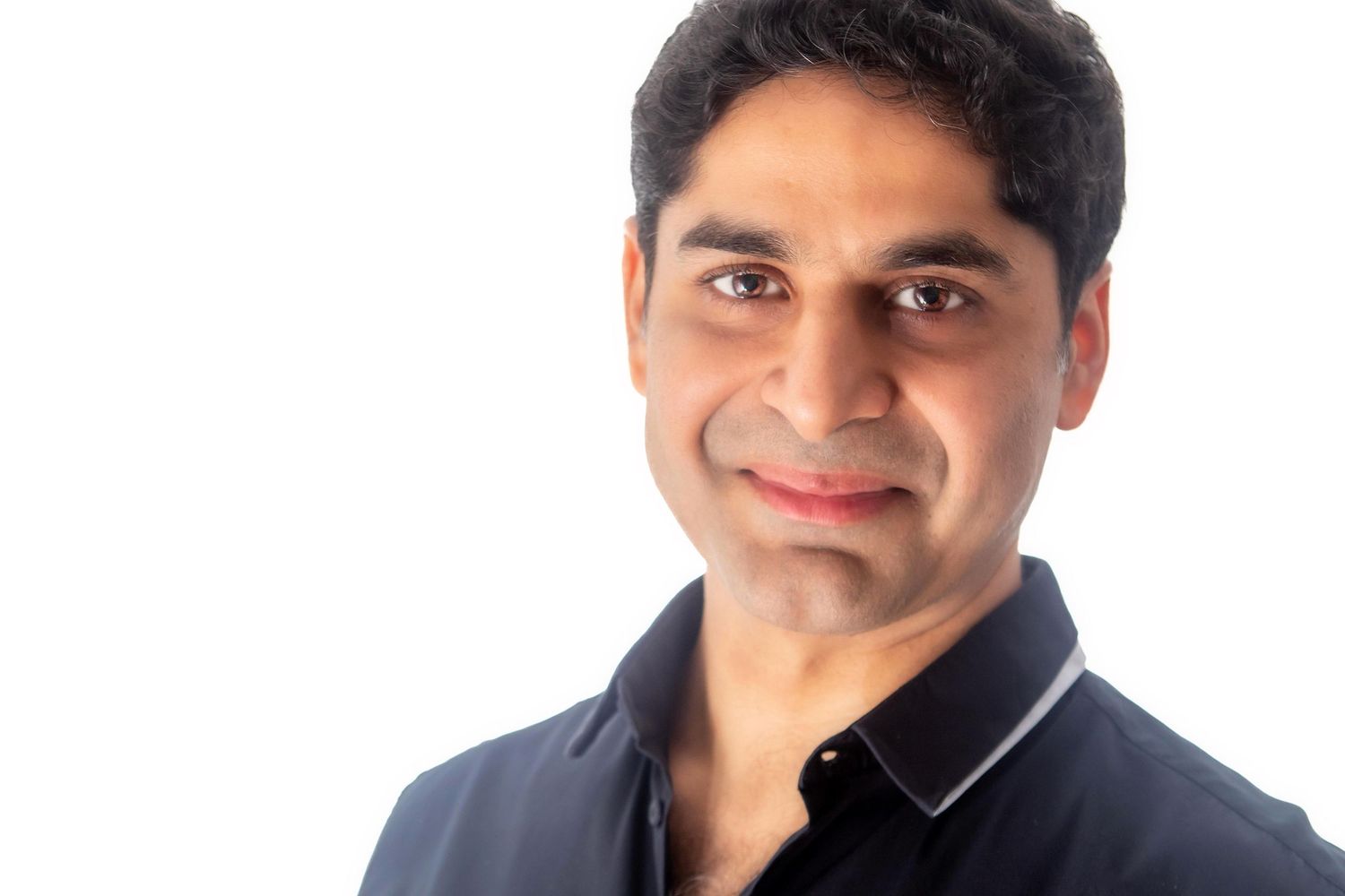 A professional portrait of a person in a black polo shirt against a white background.