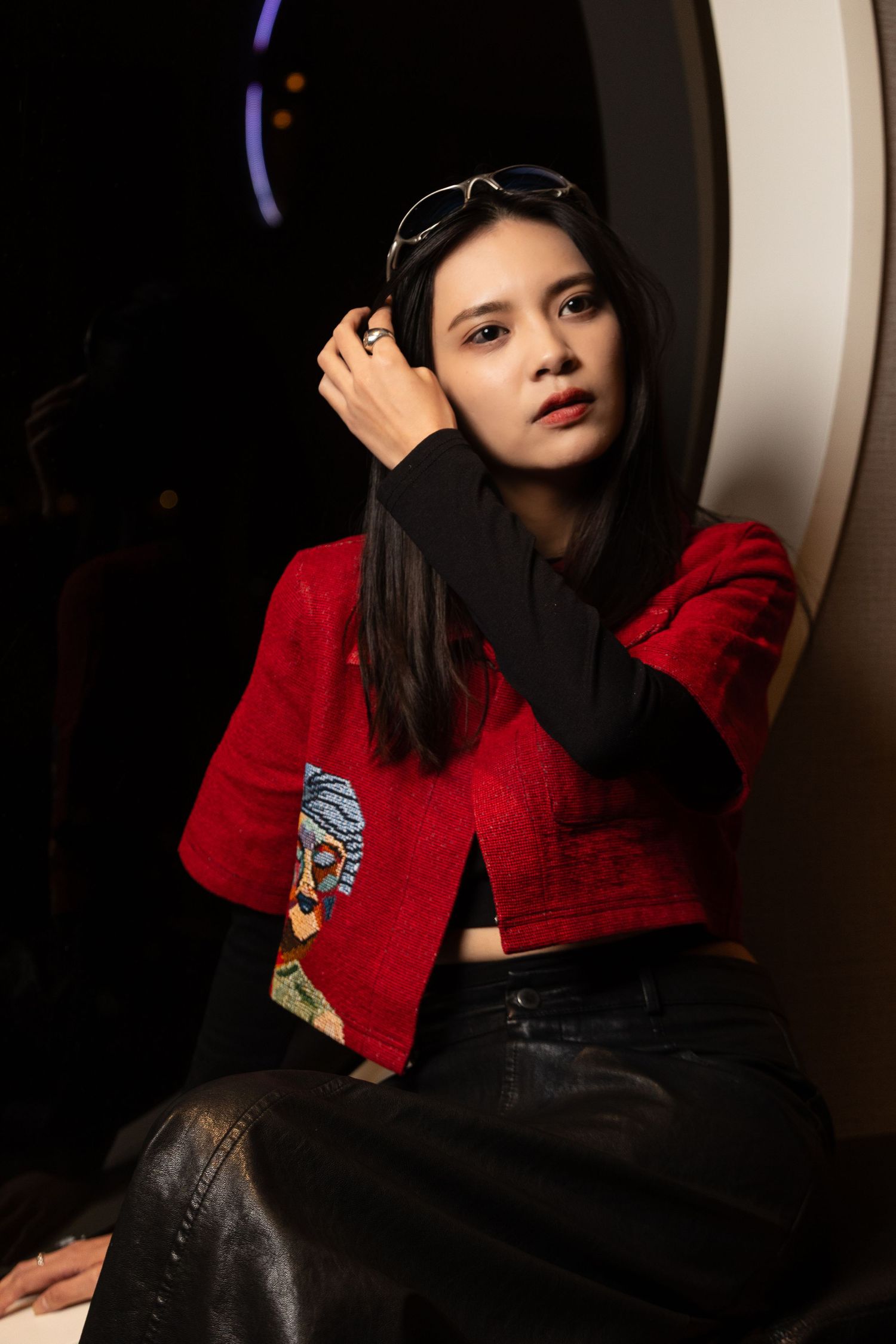 High end fashion portrait of woman in red jacket with moody lighting in studio setting