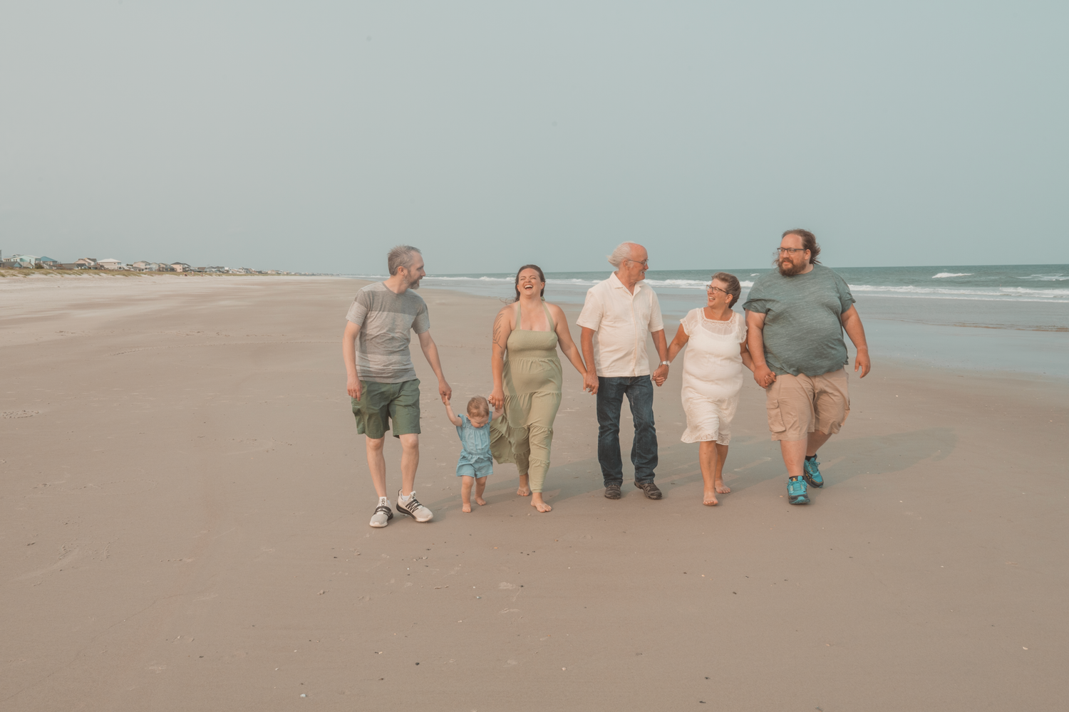 A group walks together along a serene beach shoreline during golden hour.