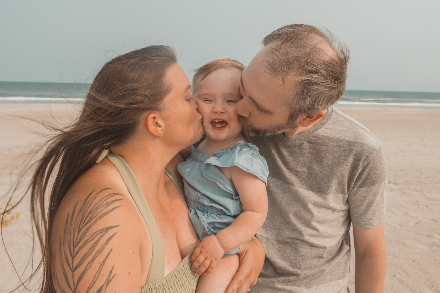 A family shares joyful moments together on a sunny beach, with matching casual attire in warm tones.
