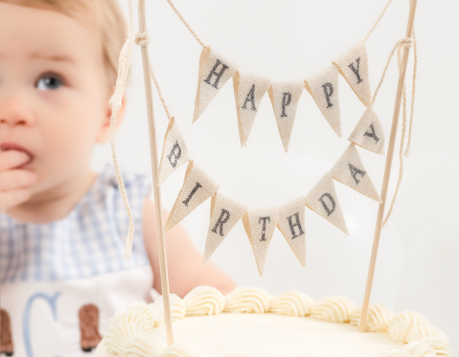 A white birthday cake with a burlap 