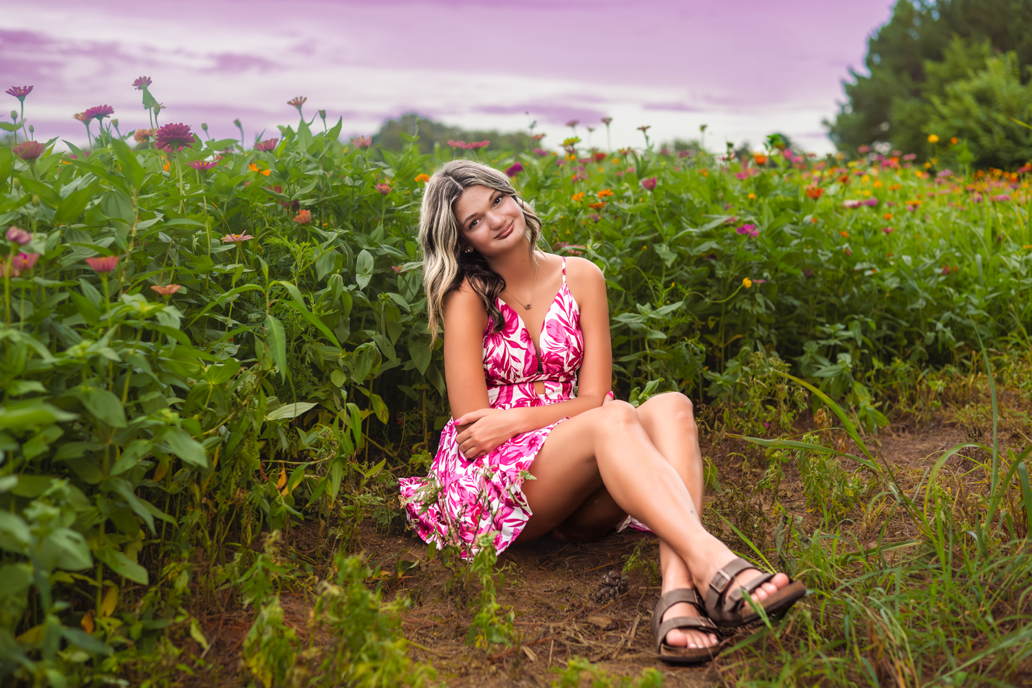 A pink floral sundress contrasts beautifully against a lush summer garden with vibrant flowers and greenery.