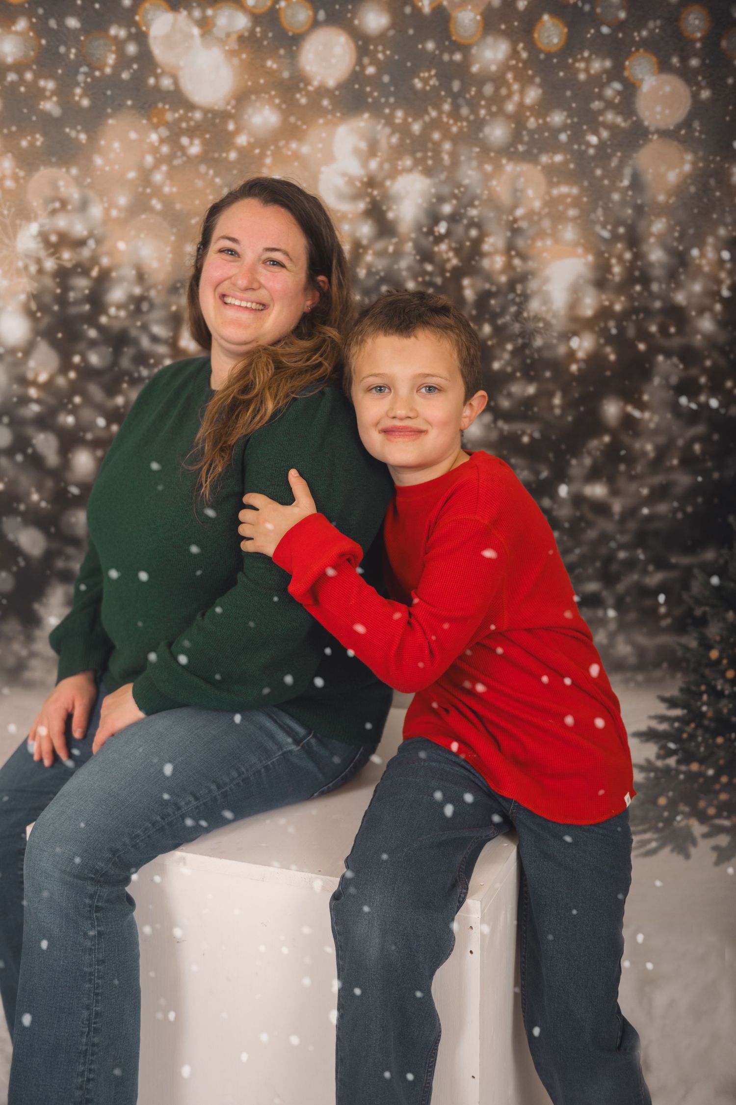 A festive holiday photo with red and green sweaters against a snowy bokeh background during a winter portrait session.
