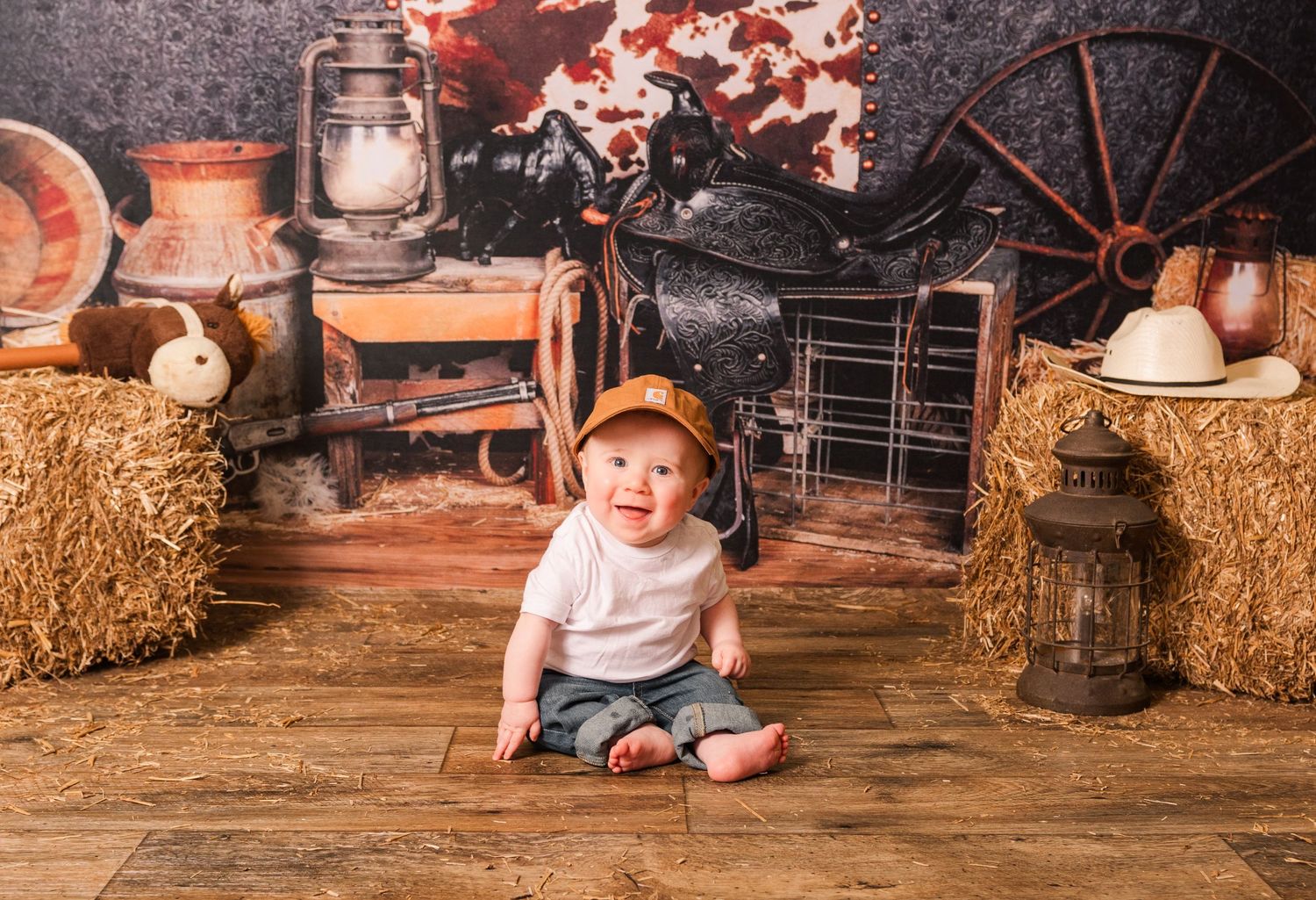 Rustic fall themed photo setup with hay bales, lantern, wooden floor and autumn decorative elements in warm tones.