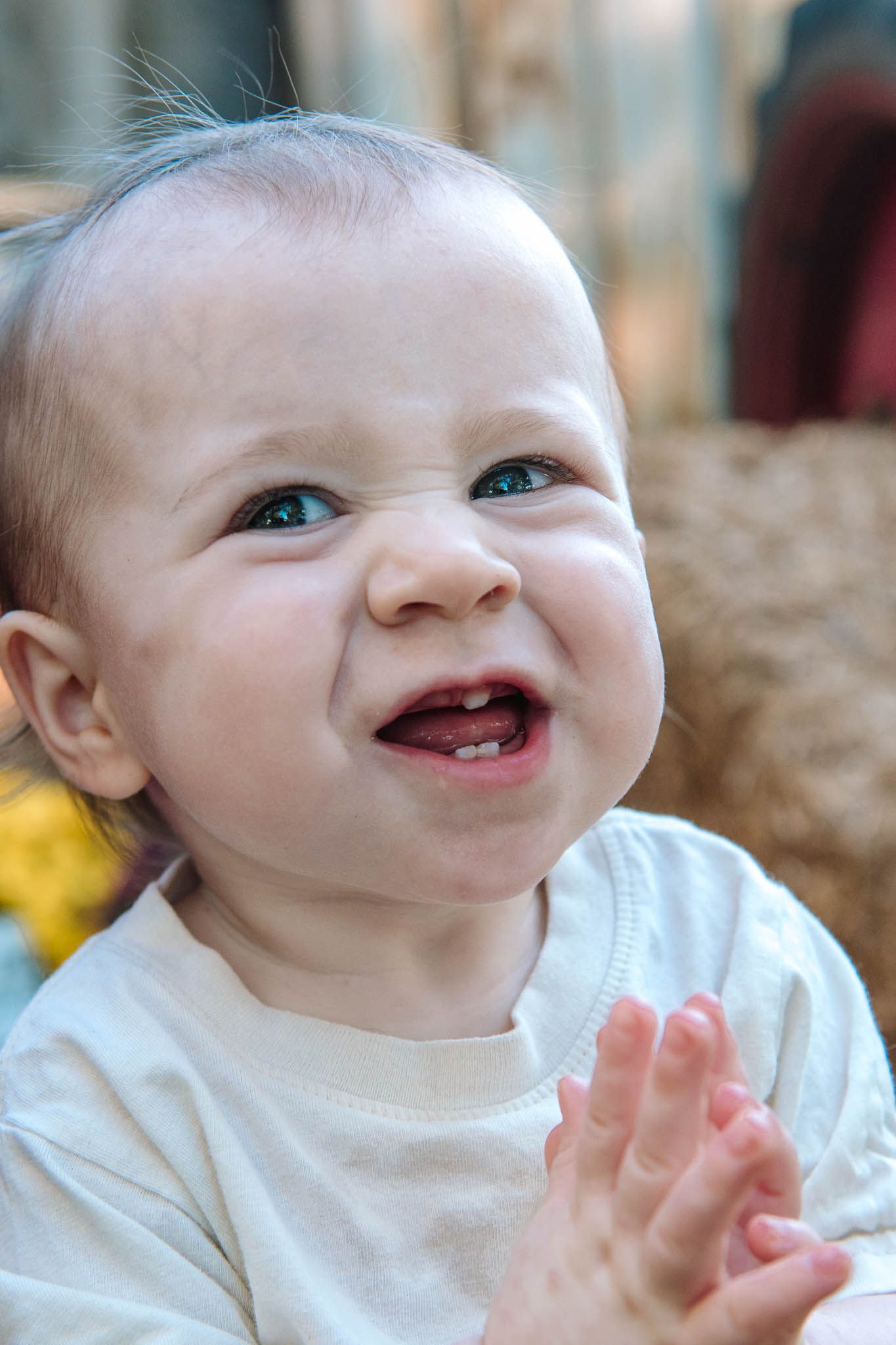 Happy baby in white shirt clapping hands and smiling with joyful expression.