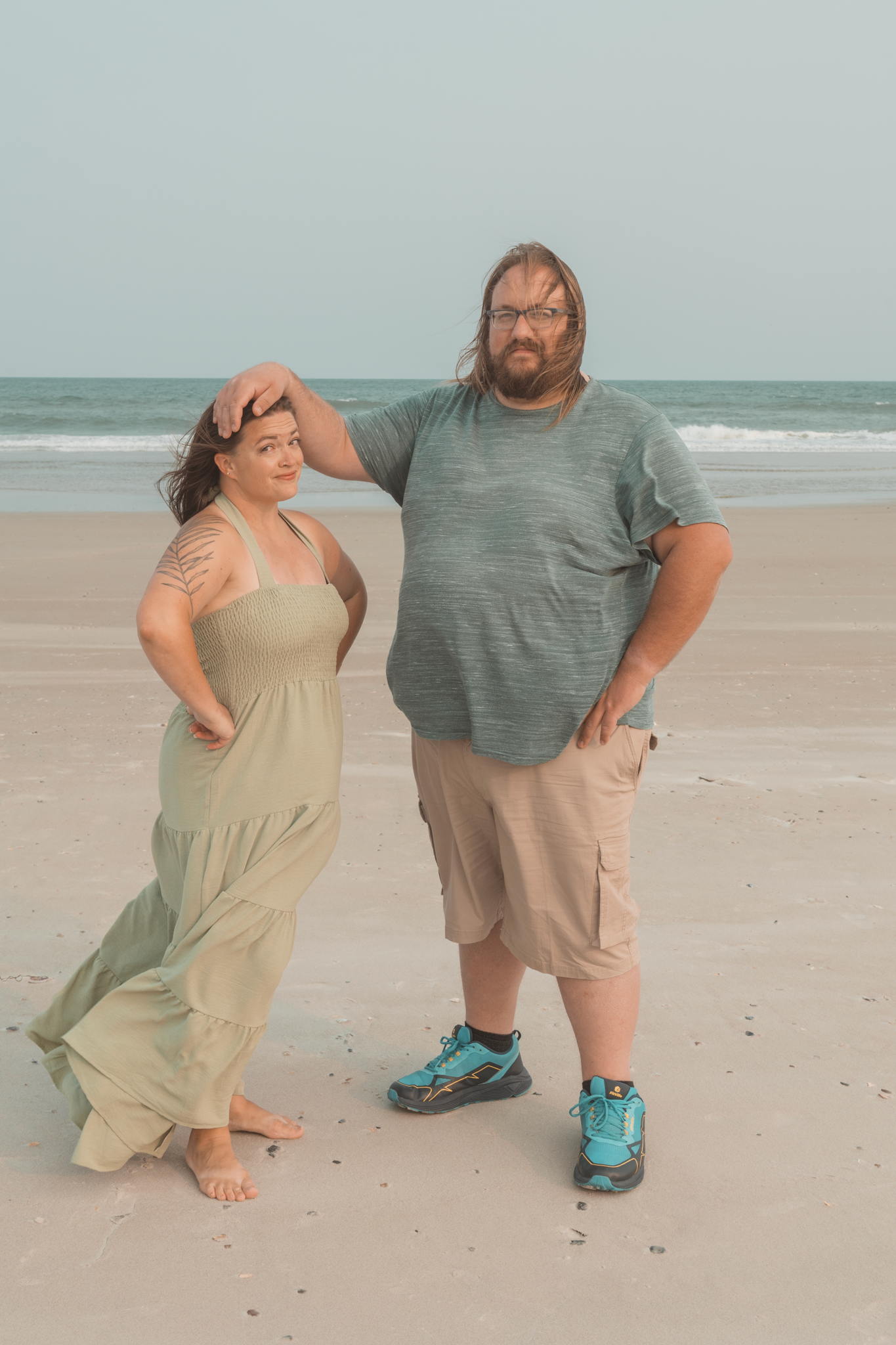 A romantic photo shoot sequence showing a couple having fun and laughing together on a sandy beach.