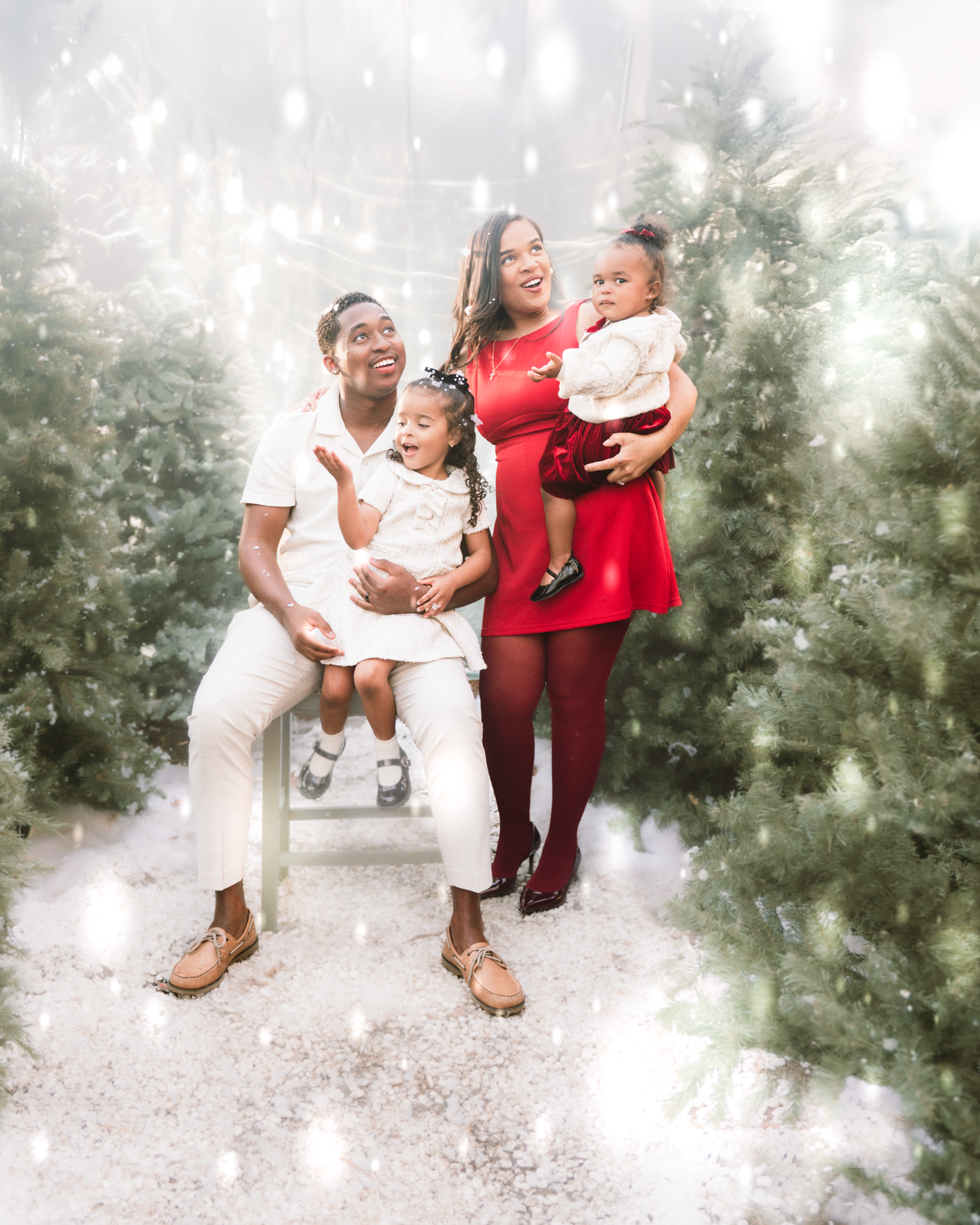 Family enjoying a candid outdoor photo session in a misty garden setting with matching white and burgundy outfits.
