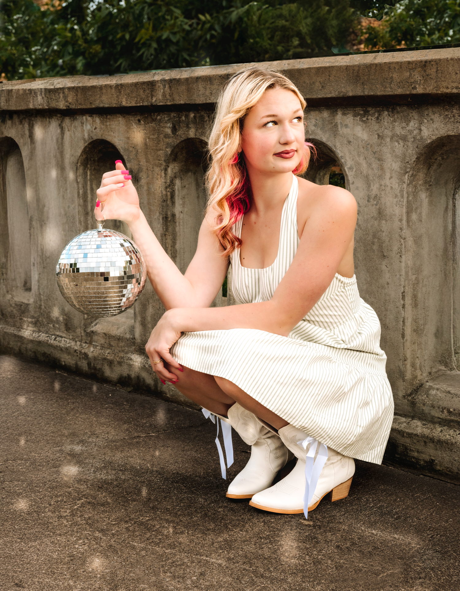 A series of four artistic portrait photos showing someone in a white dress sitting on a concrete ledge wall outdoors.