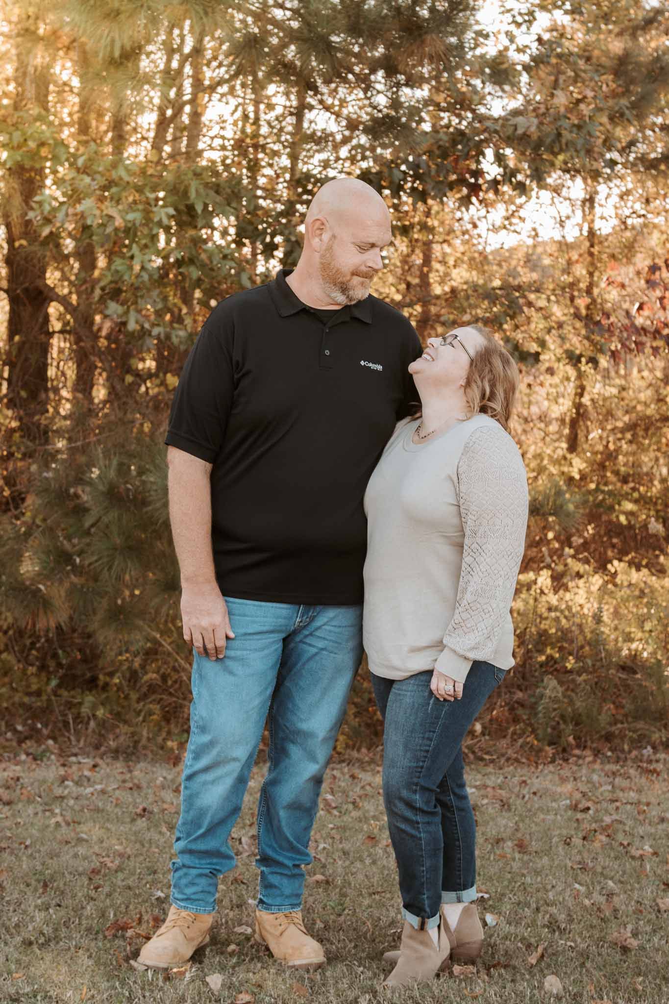 A couple shares a loving moment together in an autumn forest setting during golden hour.