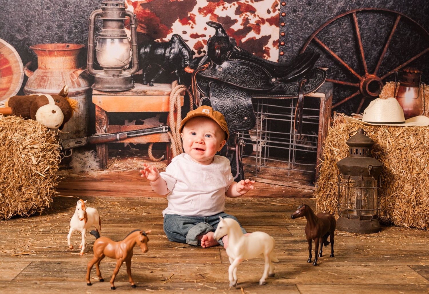 Rustic barn scene with toy farm animals, hay bales, lanterns, and decorative Western props arranged for photography.