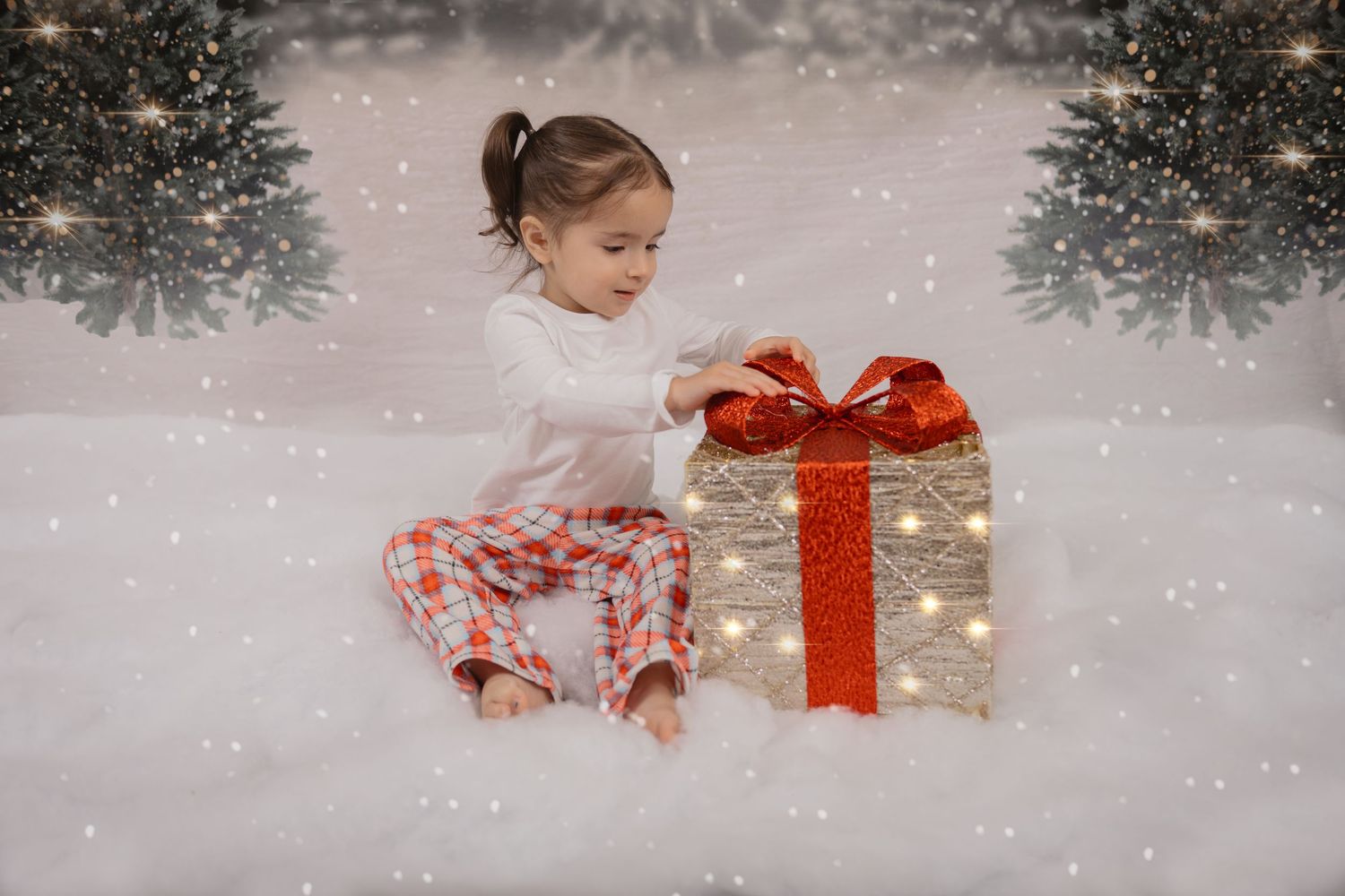 A festive holiday scene with a wrapped present glowing with lights and a red bow in falling snow.