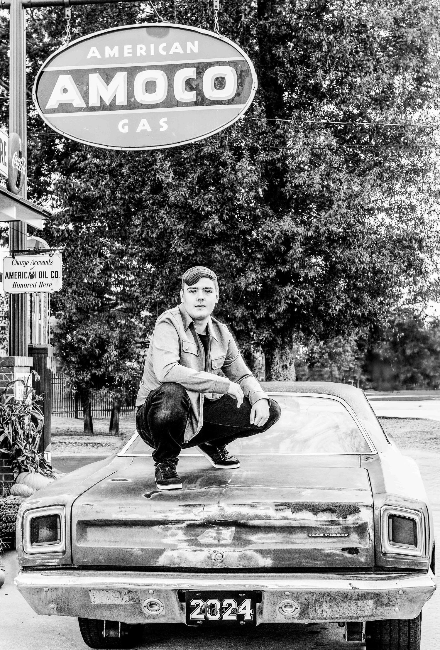 Vintage black and white photograph showing a classic car parked beneath an American Amoco gas station sign.