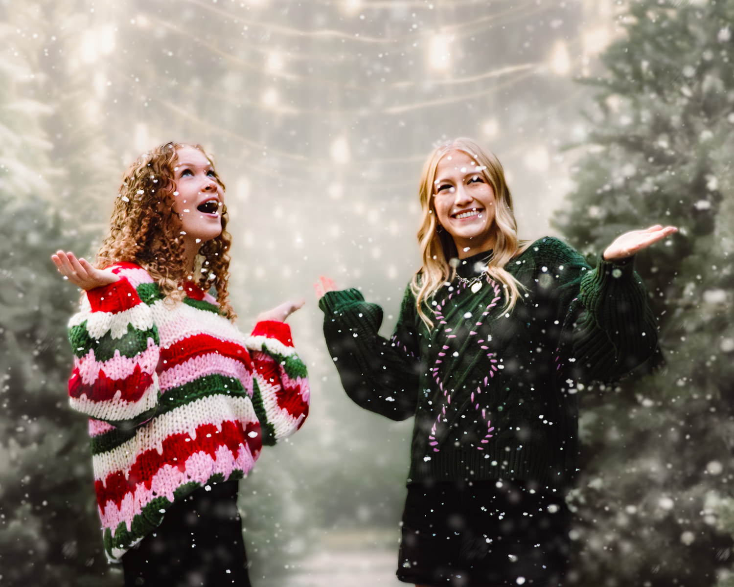 Two people in winter attire playfully catch snowflakes during a gentle snowfall in a misty forest setting.