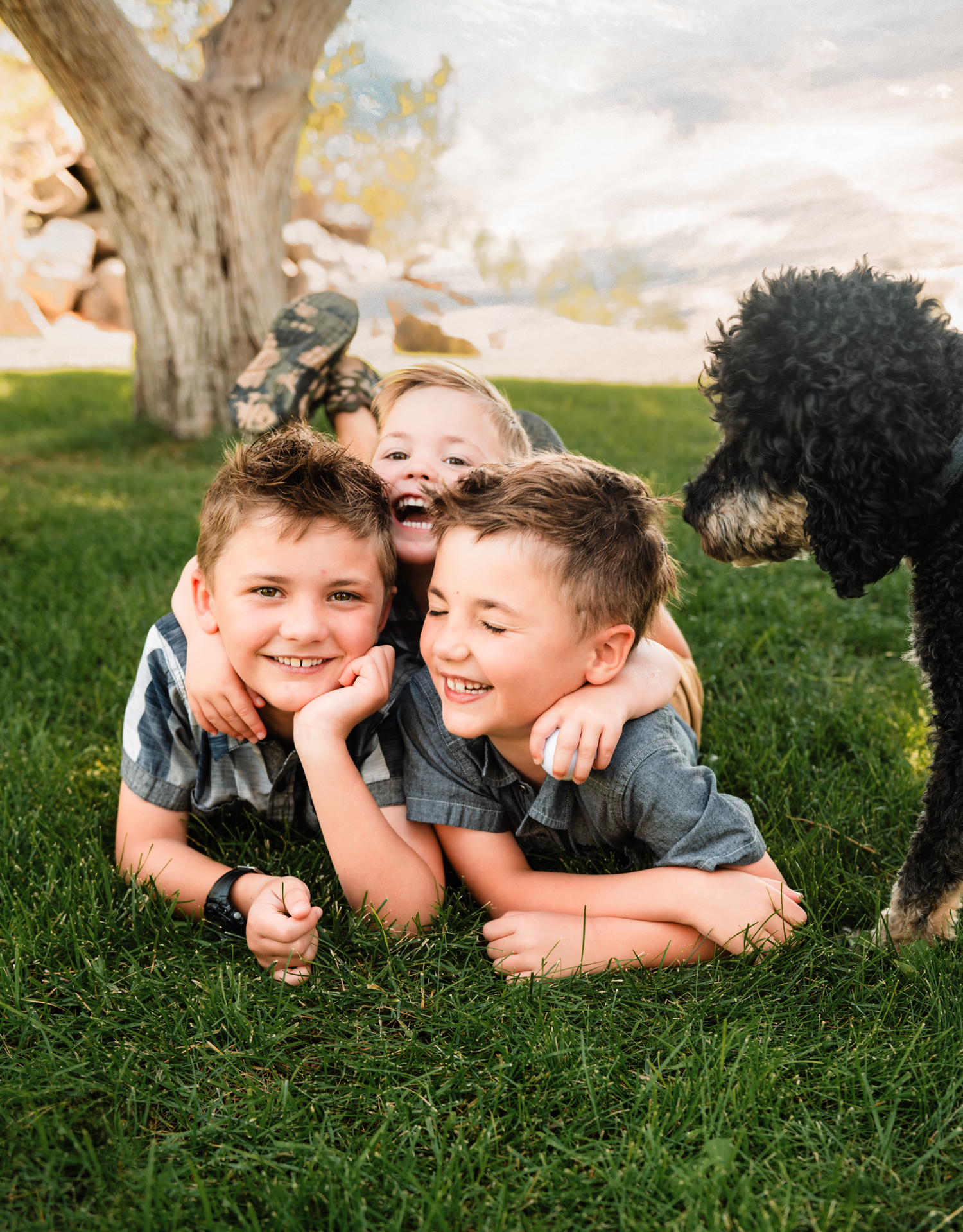 Children laying on green grass laughing and playing together on a sunny day outdoors.