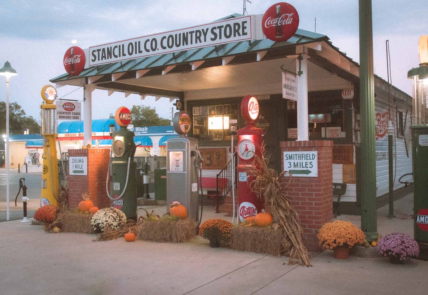 Vintage country store with retro gas pumps and Coca-Cola signs decorated with fall pumpkins and hay bales.