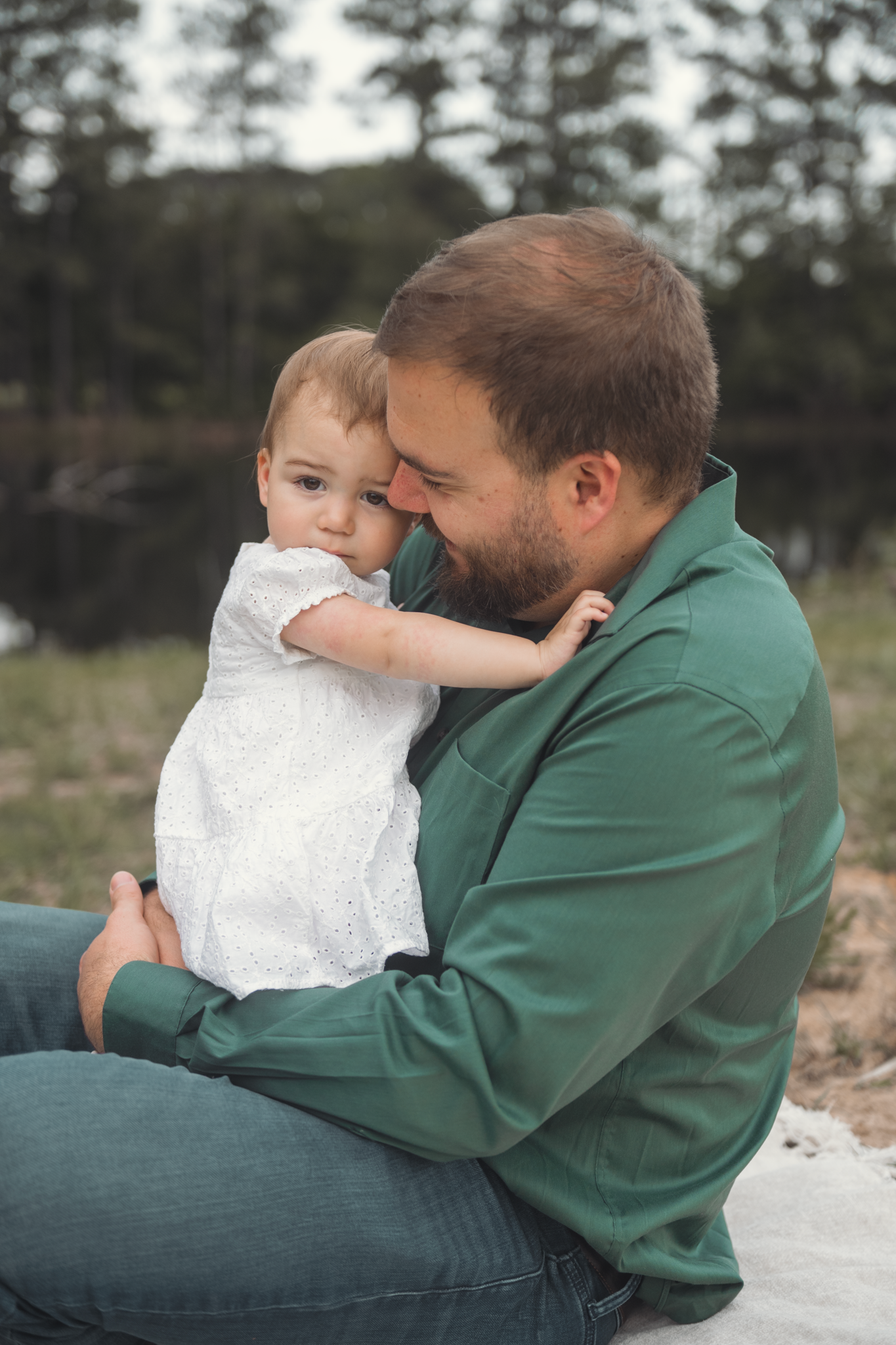 A tender moment between parent and young child outdoors as they embrace while sitting on a blanket.