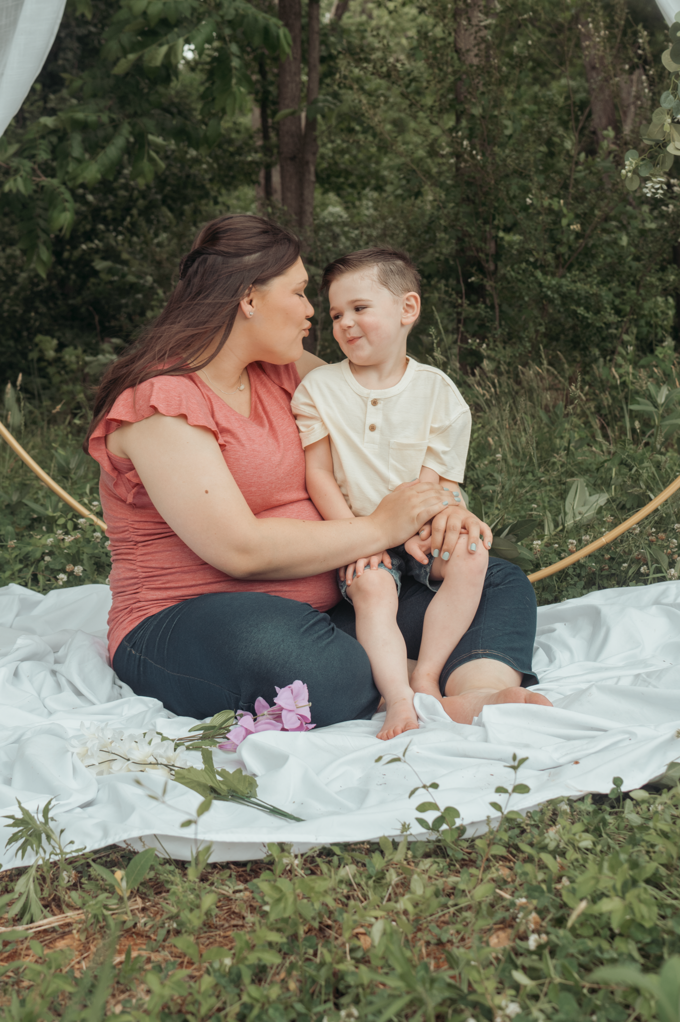 A heartwarming outdoor portrait on a white blanket in a natural wooded setting during a photo session.