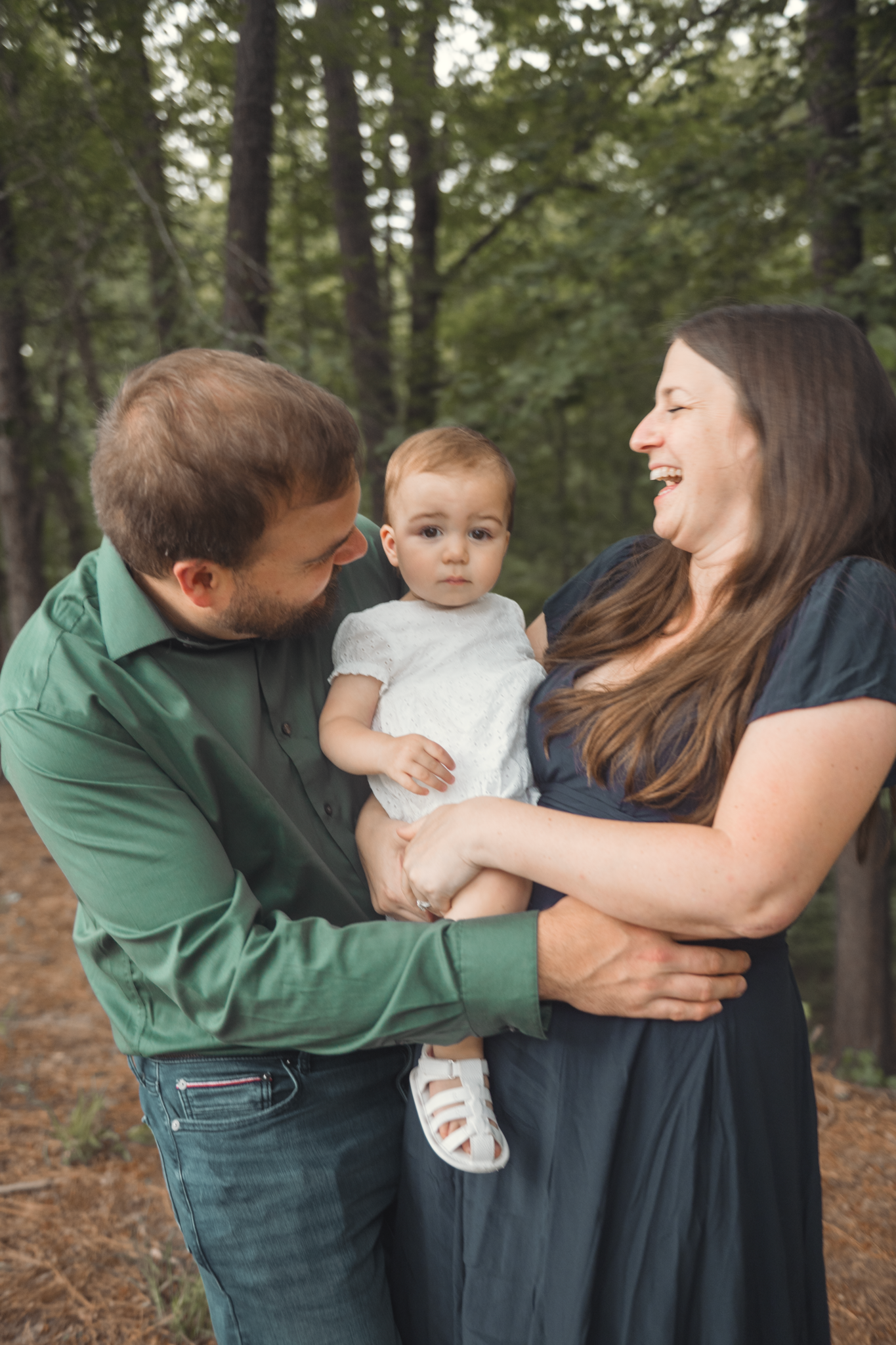 A happy family shares a joyful moment together while standing in a peaceful wooded forest setting.