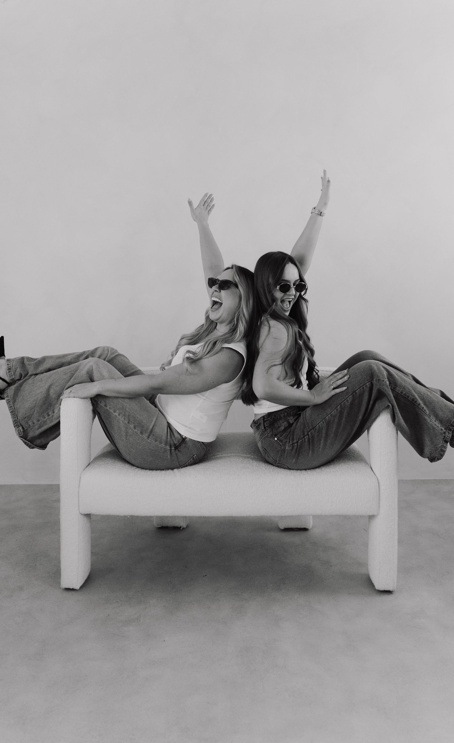 A black and white photo series showing someone lounging and posing on a modern white sofa.