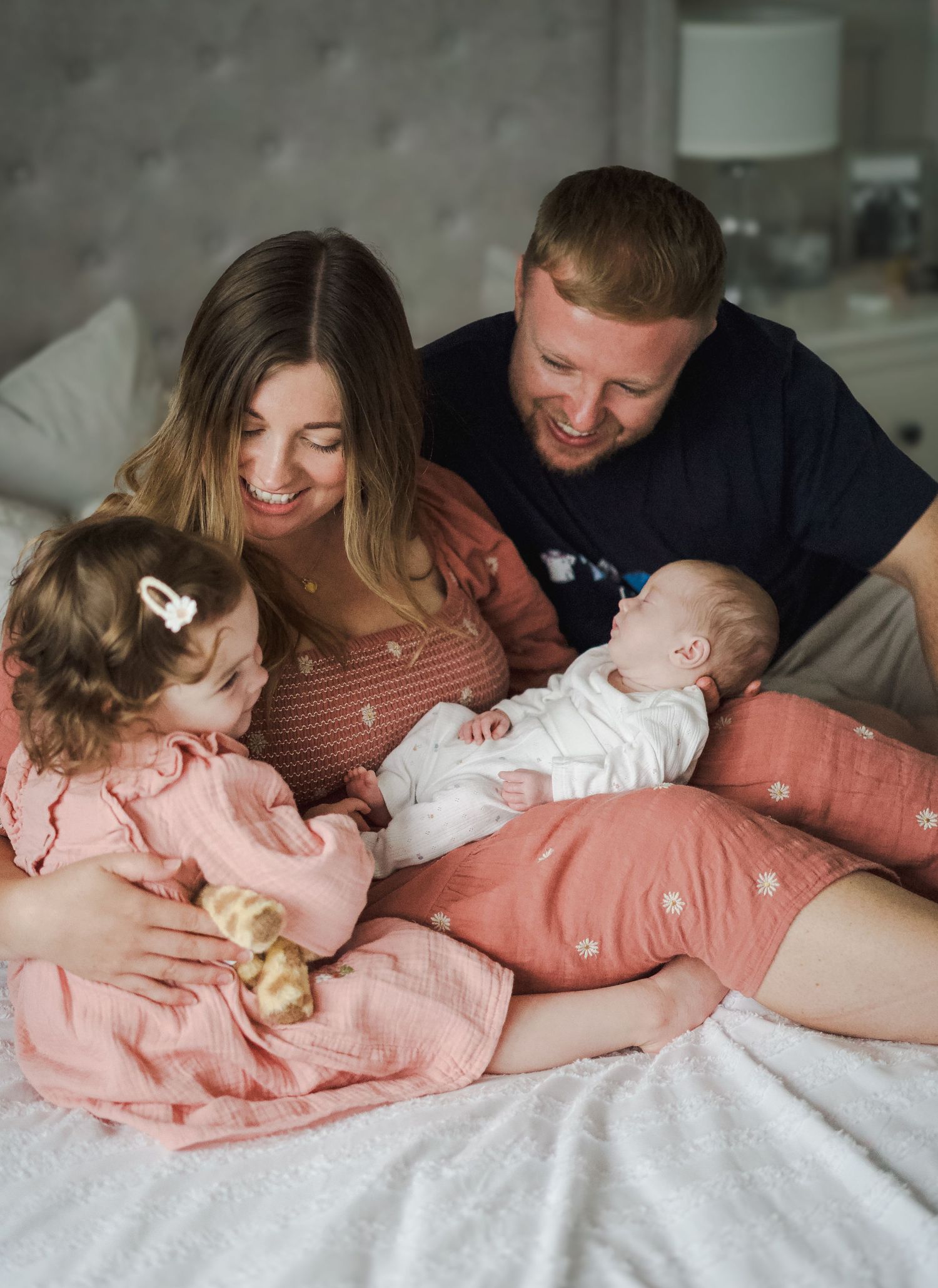 A family sharing loving moments together on white bedding.