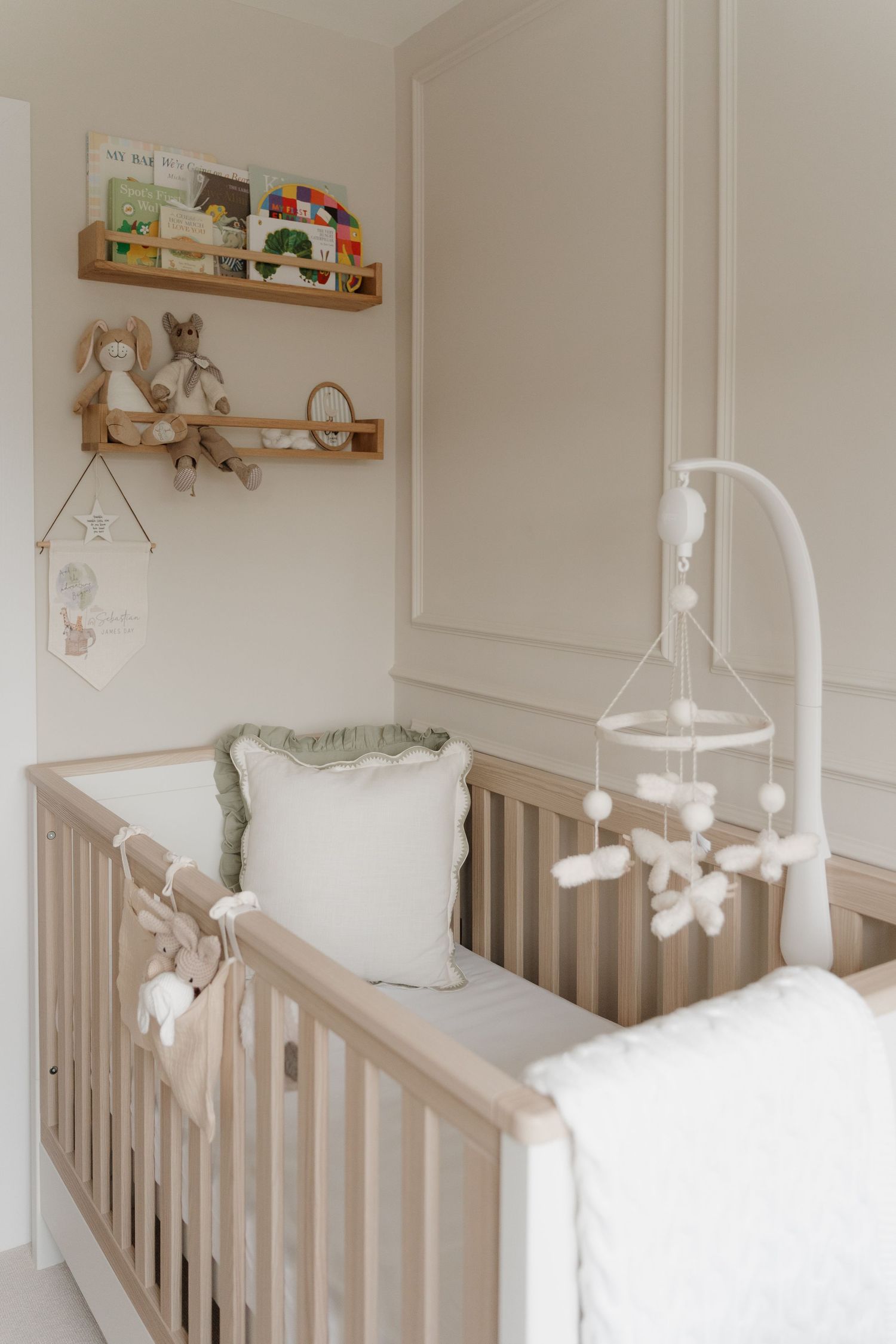 Soft and serene nursery interior with white crib and floating shelves displaying stuffed animals and decor. Newborn photography Derbyshire.