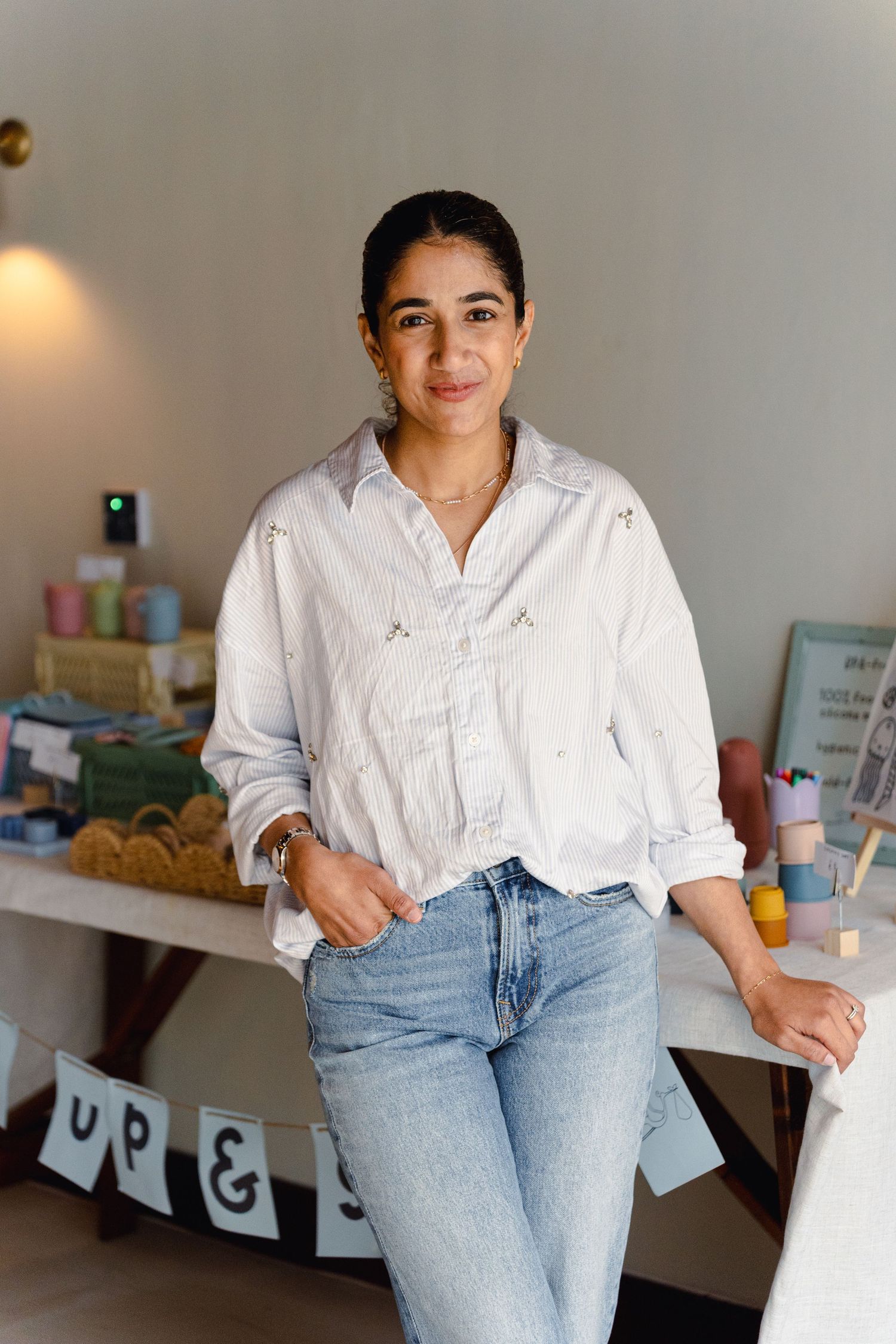 Casual lifestyle portrait showing someone in a crisp white button-down shirt and light wash jeans leaning against a counter.